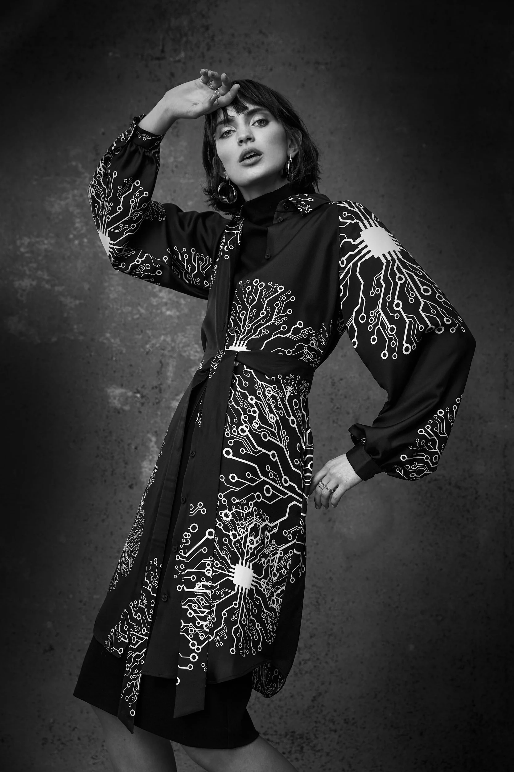 Hellmuth Lookbook 2019: bestickter Mantel KUNIS in Schwarzweiß, Pose mit erhobenem Arm