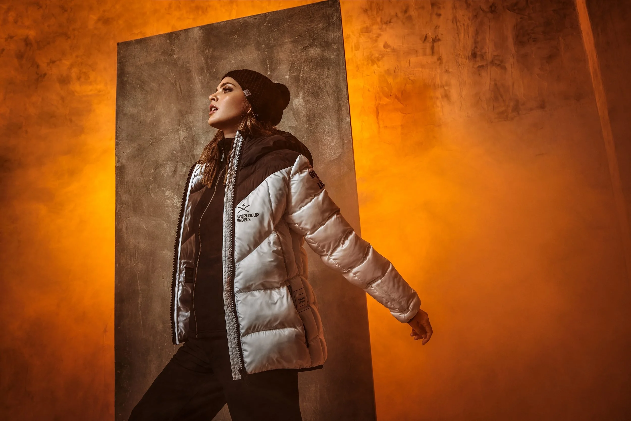 Frau in silberner Daunenjacke vor orangefarbenem Licht