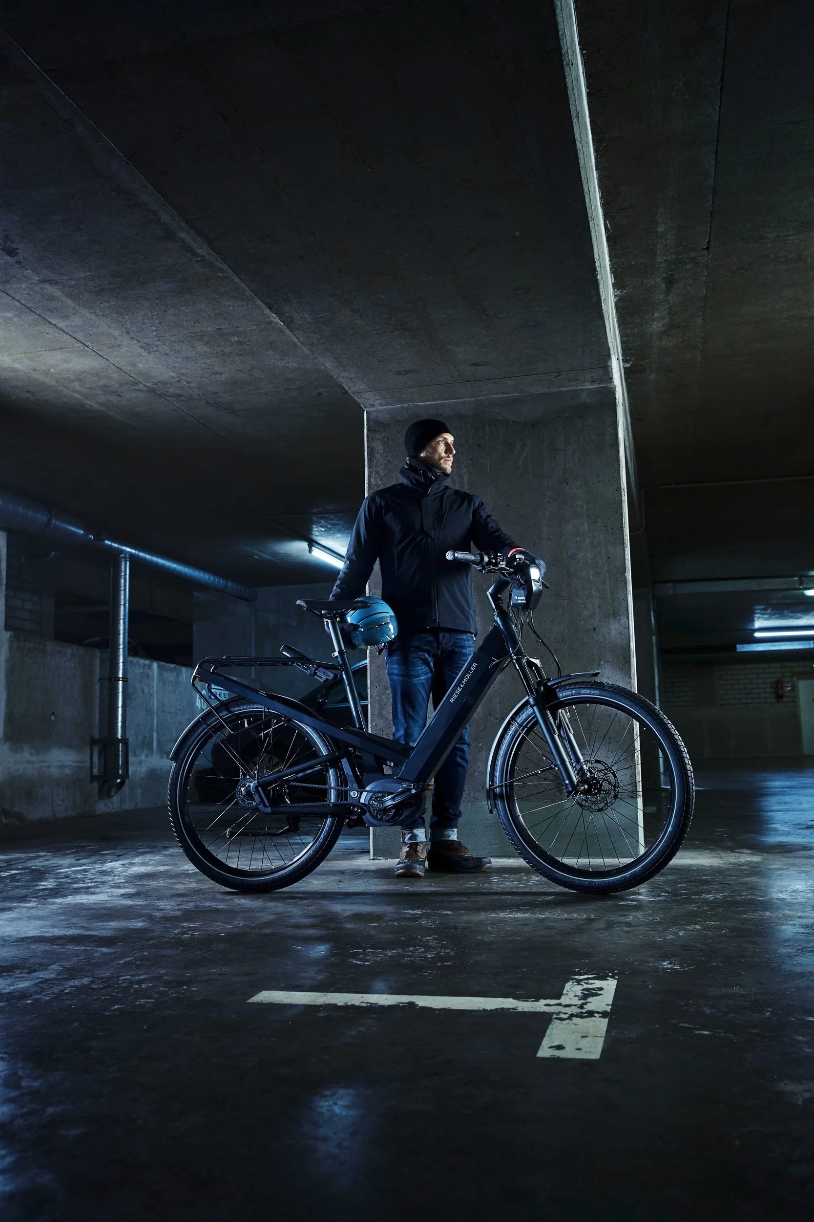 Fahrer steht mit E-Bike in dunkler Tiefgarage