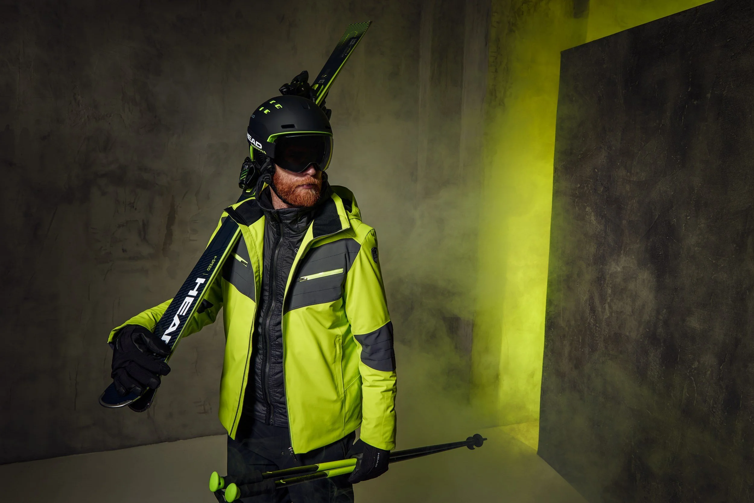 Skifahrer in giftgrüner Jacke mit Ski auf der Schulter