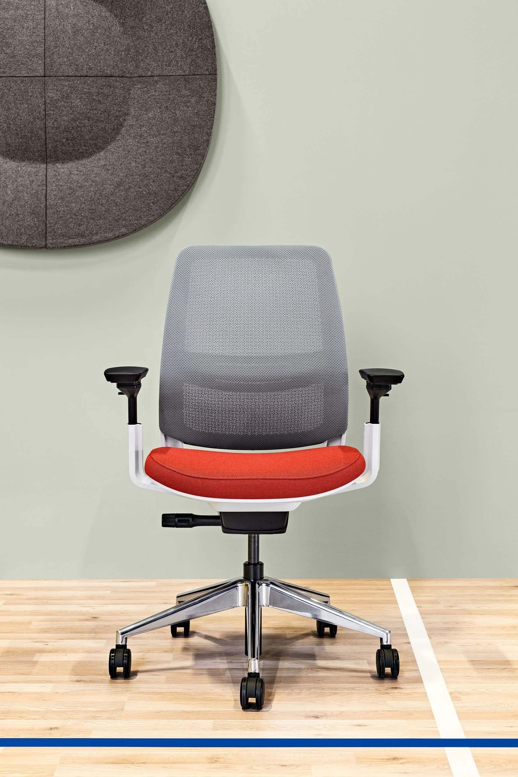 Steelcase Bürostuhl mit rotem Sitz auf Turnhallenboden mit Spielfeldlinie