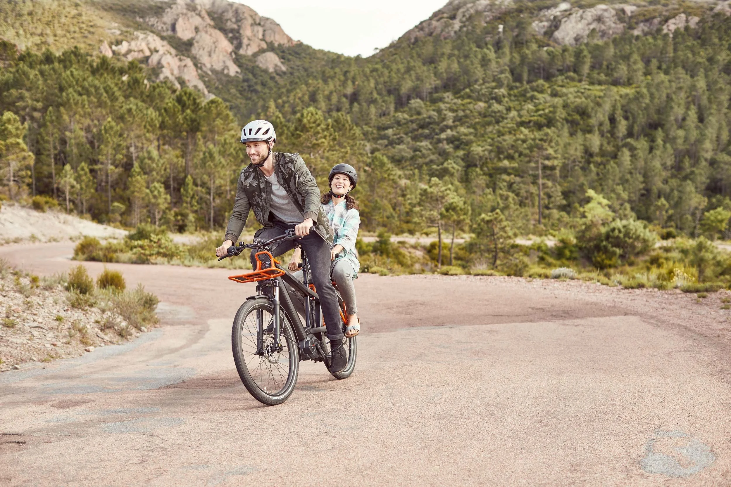 Vater und Kind fahren E-Bike durch sonniges Bergtal