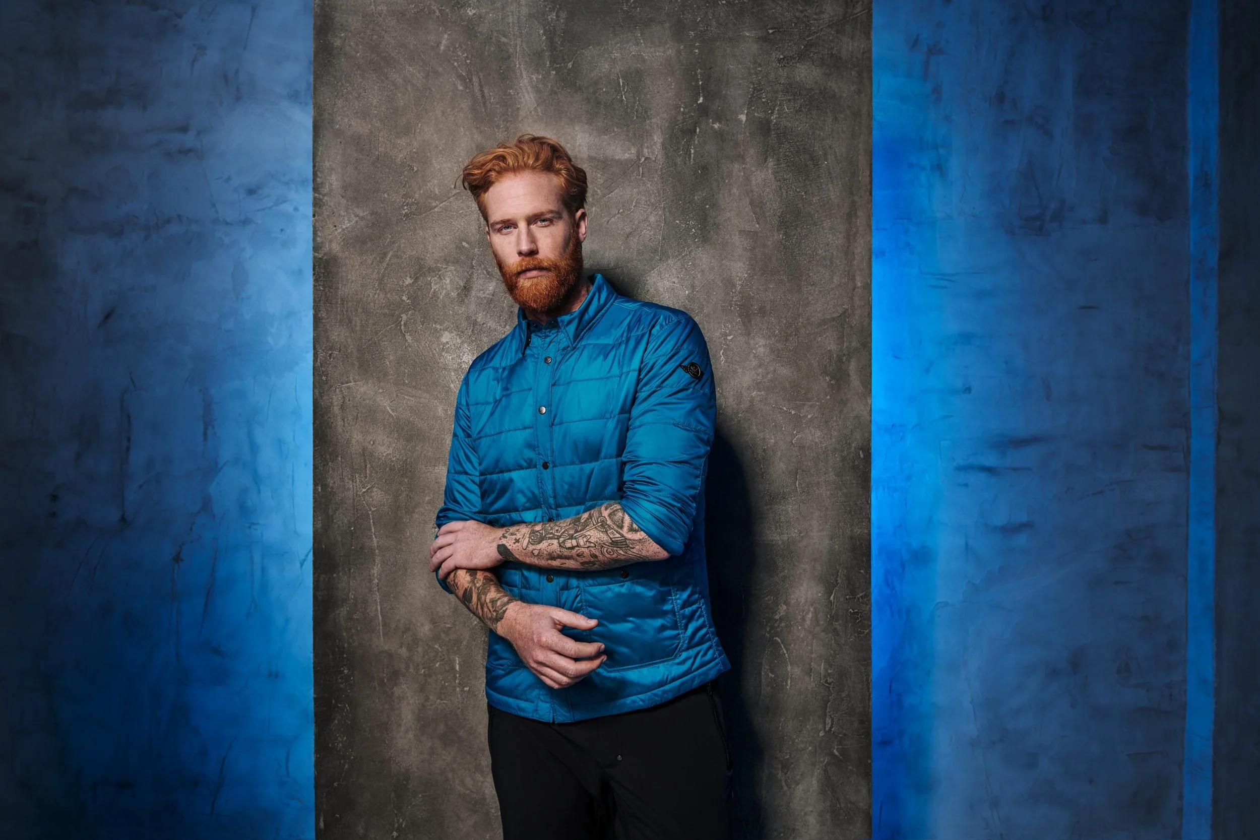 Mann in türkiser Steppjacke vor blauer Wand