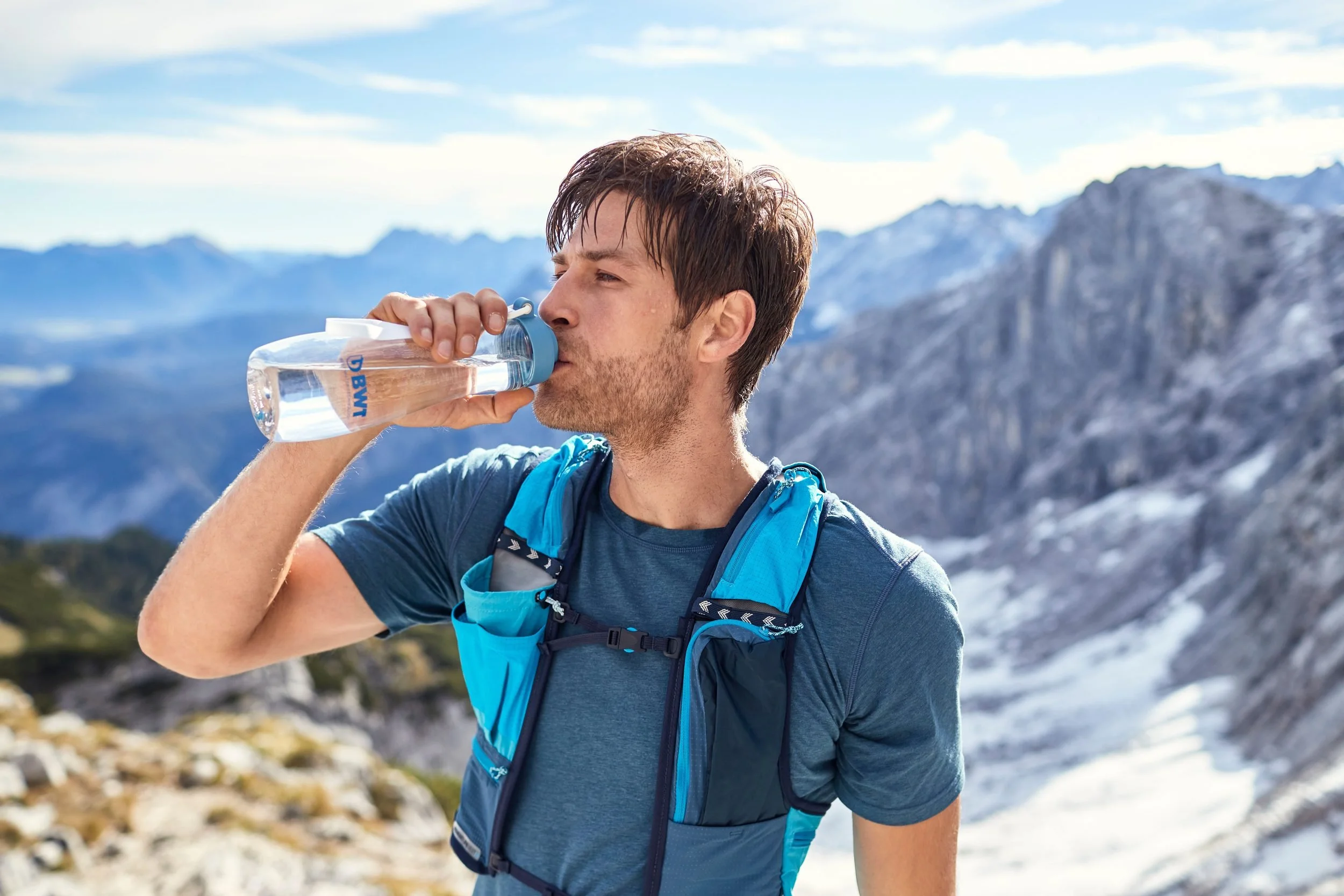 Bergsportler trinkt aus BWT-Flasche in schroffer Felslandschaft