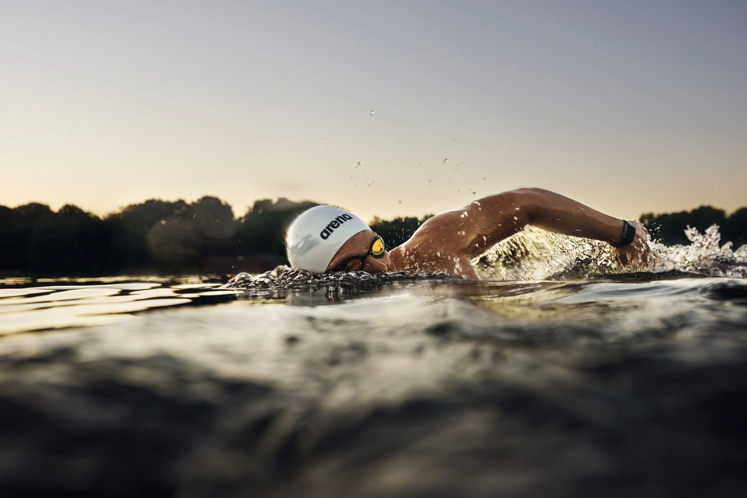 Schwimmer-Editorial von Tim Wendrich: Kraulschwimmer bei Sonnenaufgang, ruhige Wasseroberfläche
