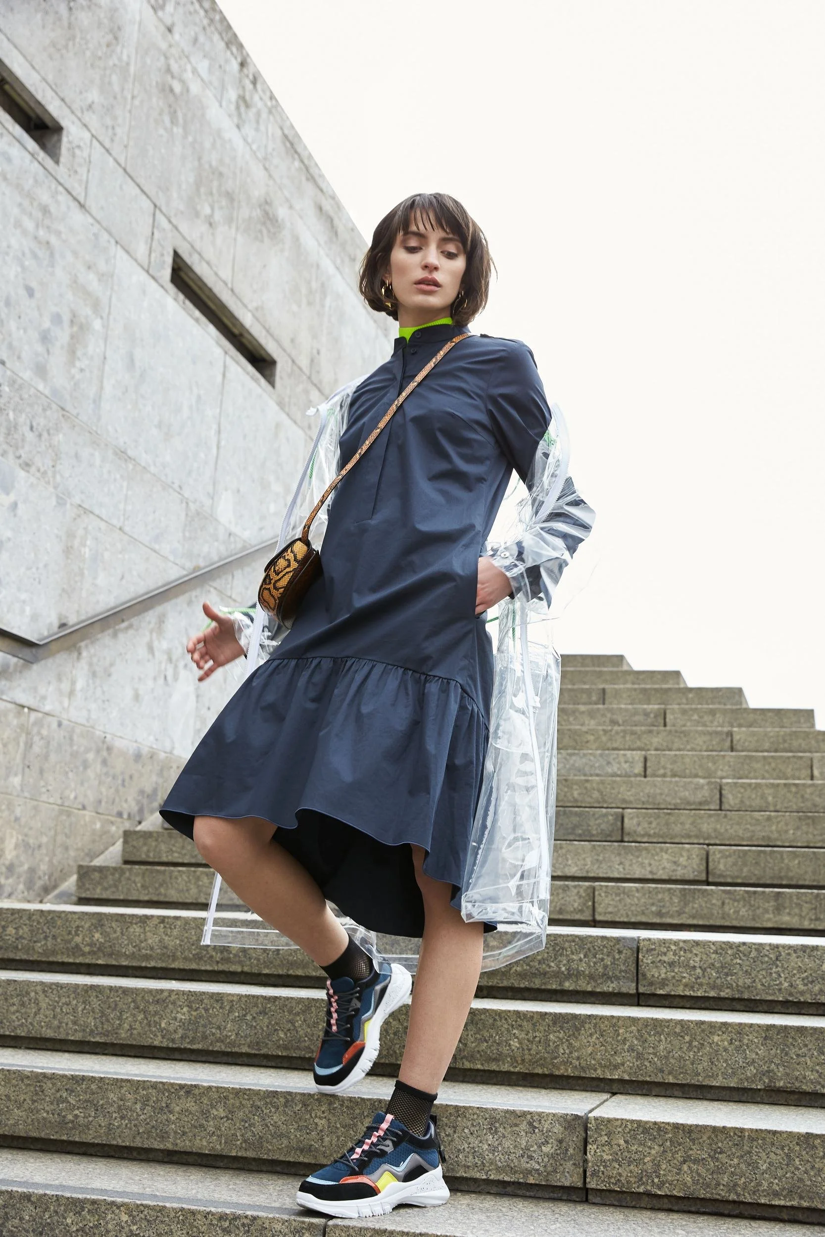 Hellmuth Lookbook 2019: blaues Volantkleid KISHA mit Umhängetasche auf einer Treppe