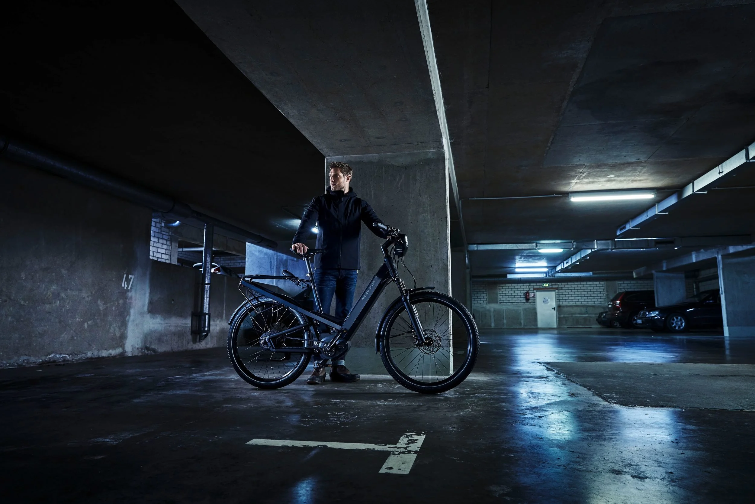 Fahrer steht neben E-Bike an Betonsäule