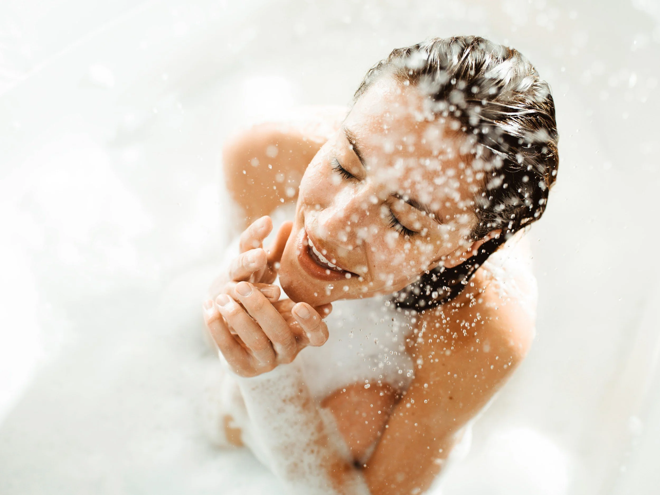 Frau in der Badewanne mit Schaum und Wasserspritzern