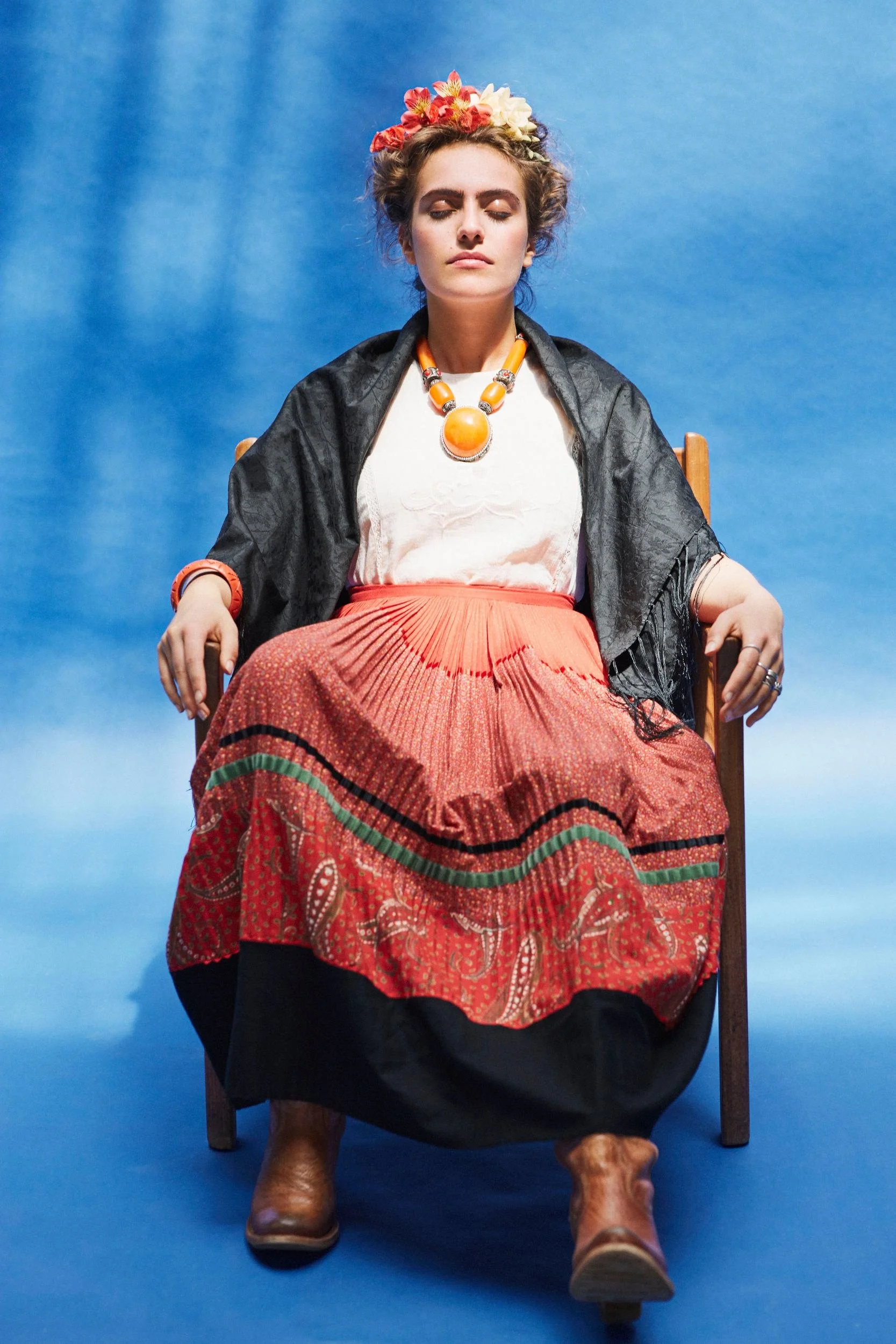 Sitzende Pose mit schwarzem Umhang und rotem Rock