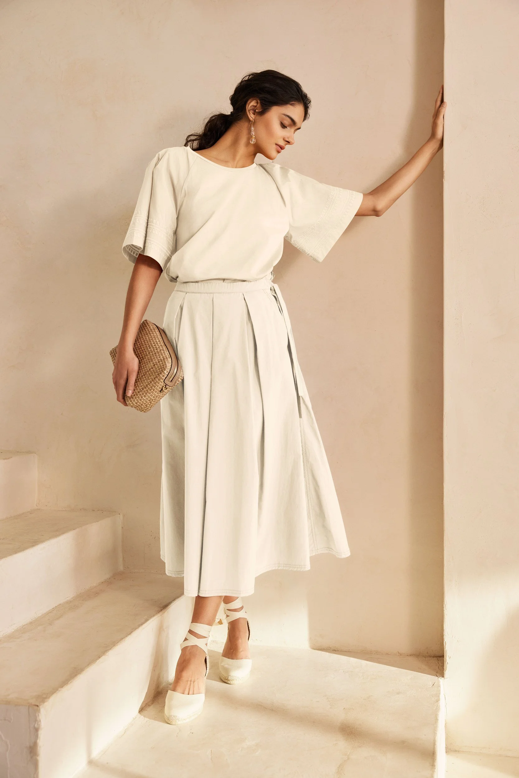Modehaus Zinser Frühjahr-Sommer 2024: cremefarbener Look mit weitem Rock auf der Treppe