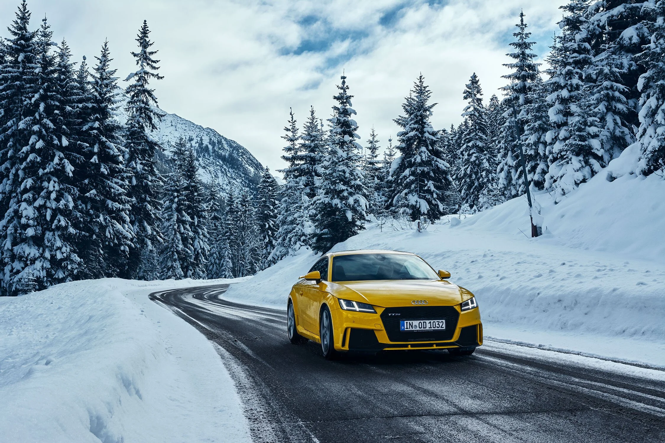 Gelber Audi TT RS auf verschneiter Bergstraße zwischen tief verschneiten Tannen – Retusche Bildergut.