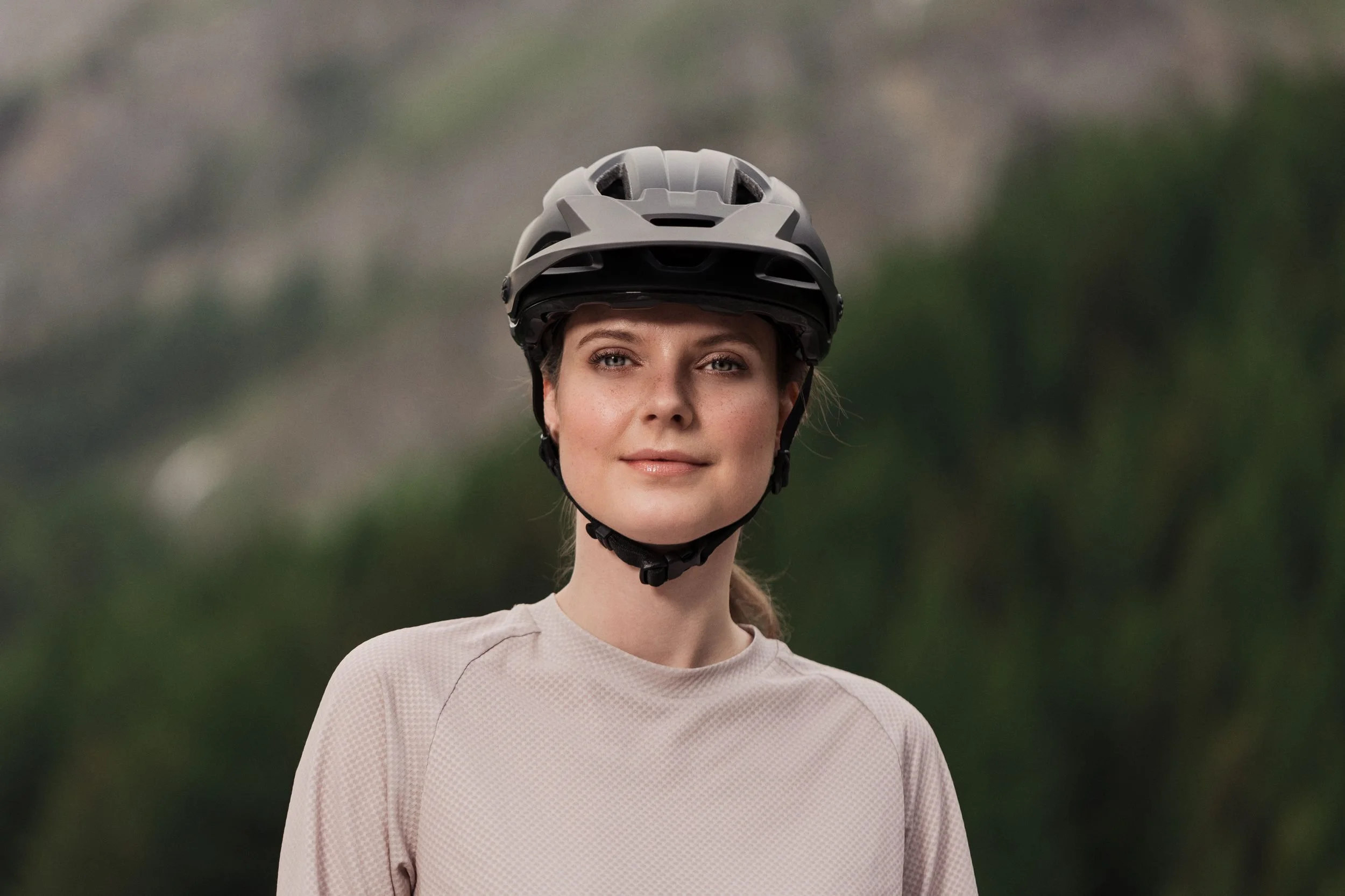 Mountainbikerin mit Helm vor grünem Tal