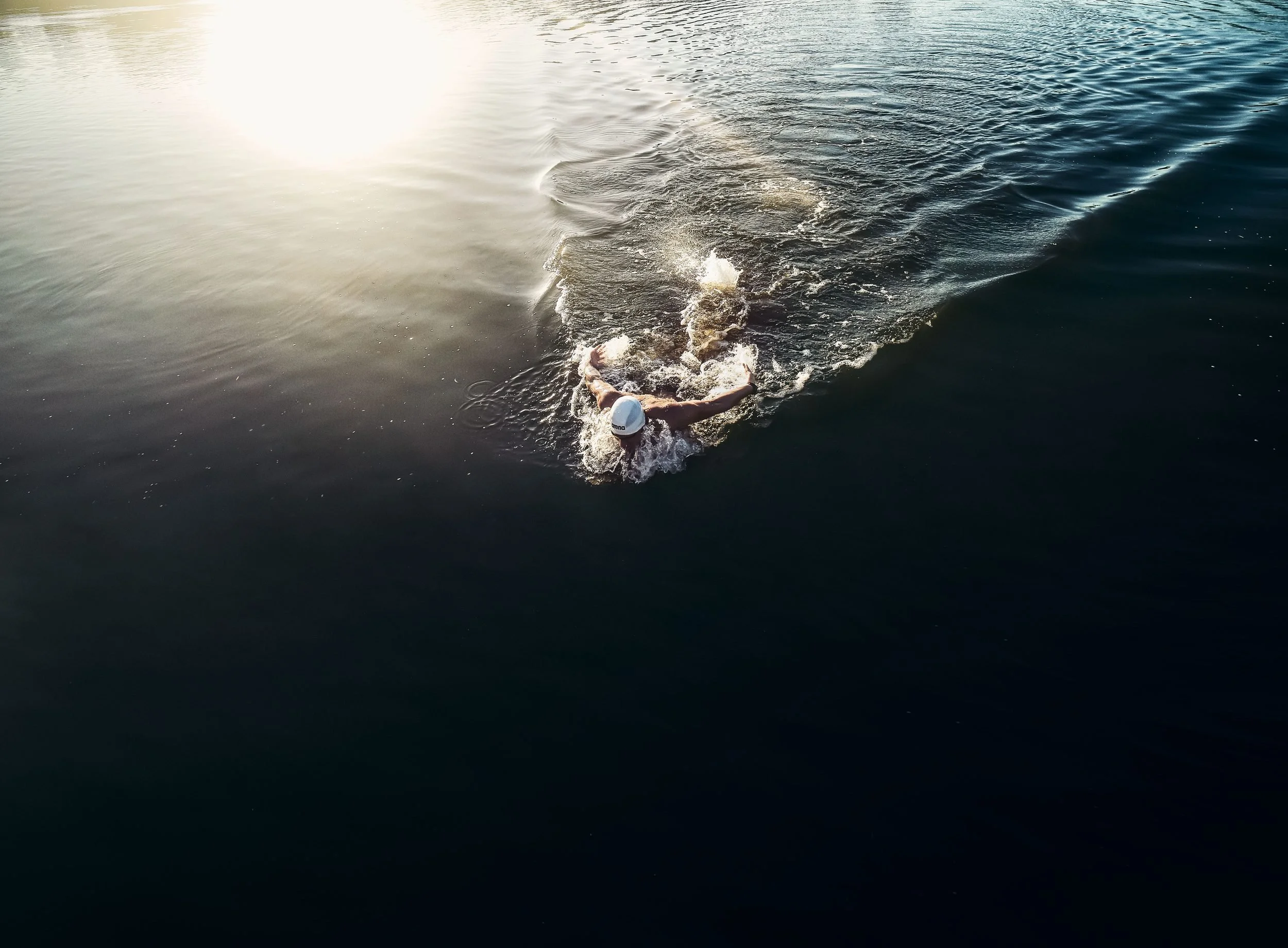 Schwimmer-Editorial von Tim Wendrich: Drohnenaufsicht, Schwimmer zieht seine Bahn durch das offene Wasser