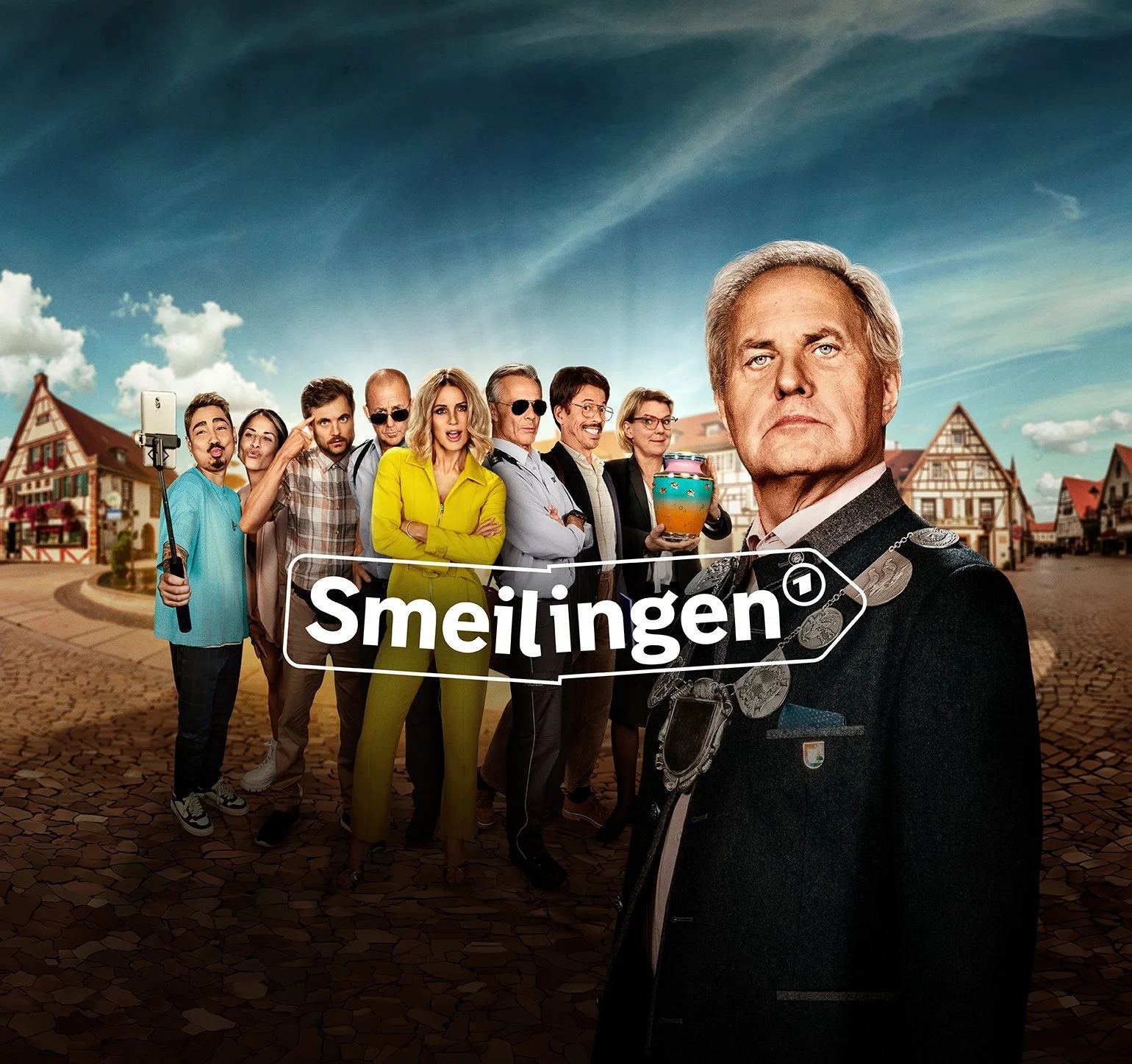 Skurriles Dorfensemble mit Urne vor Fachwerk-Marktplatz, ARD Mediathek Smeilingen – Composing von Bildergut.
