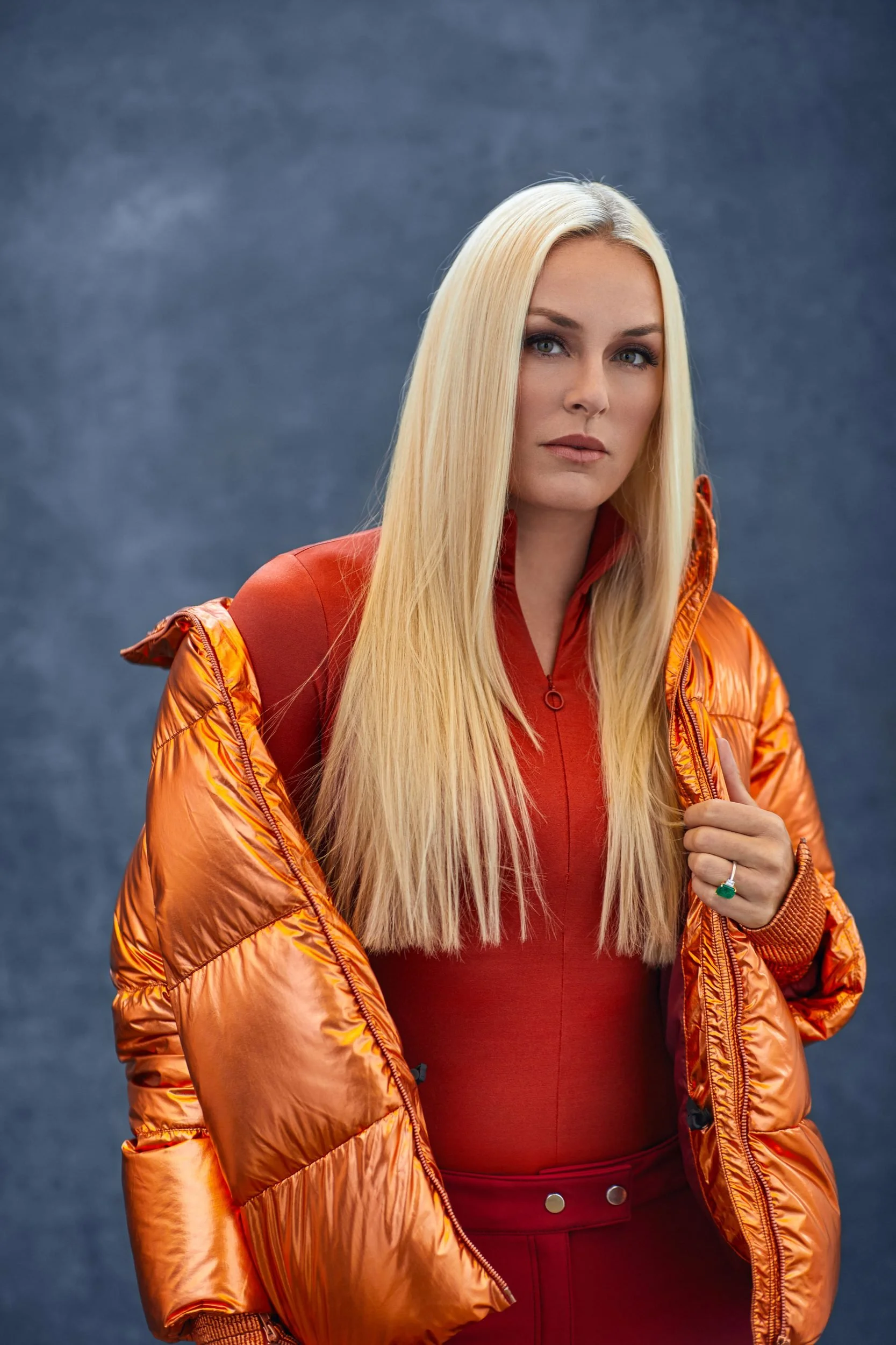 Porträt in orangefarbener Daunenjacke vor blauem Fond