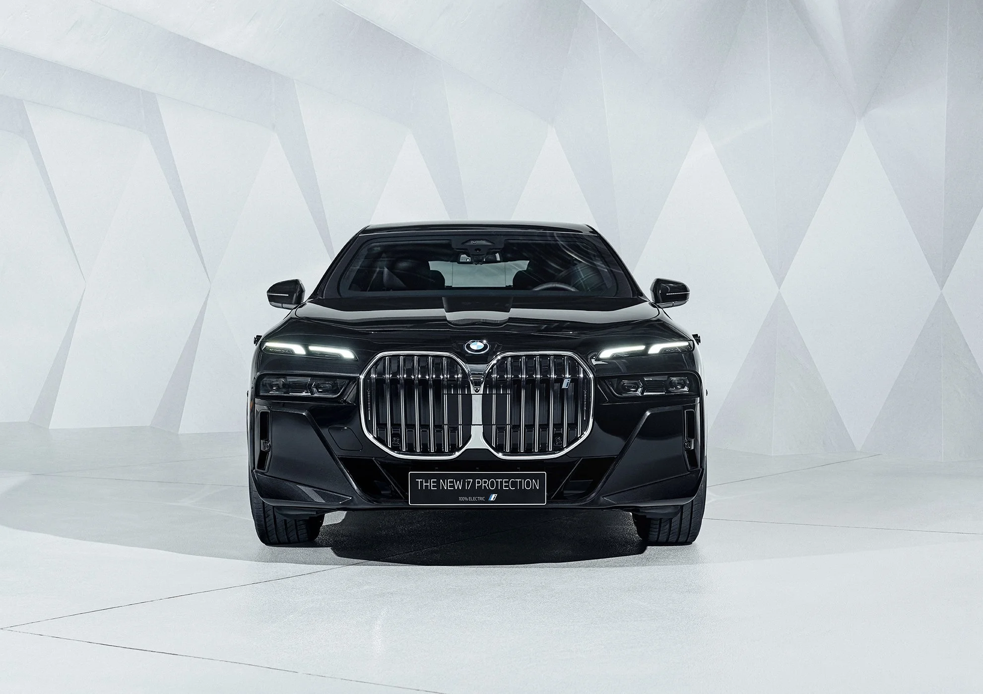 Schwarzer BMW i7 Protection in Frontansicht in hellem, kantigem Studioraum – High-End-Retusche von Bildergut.