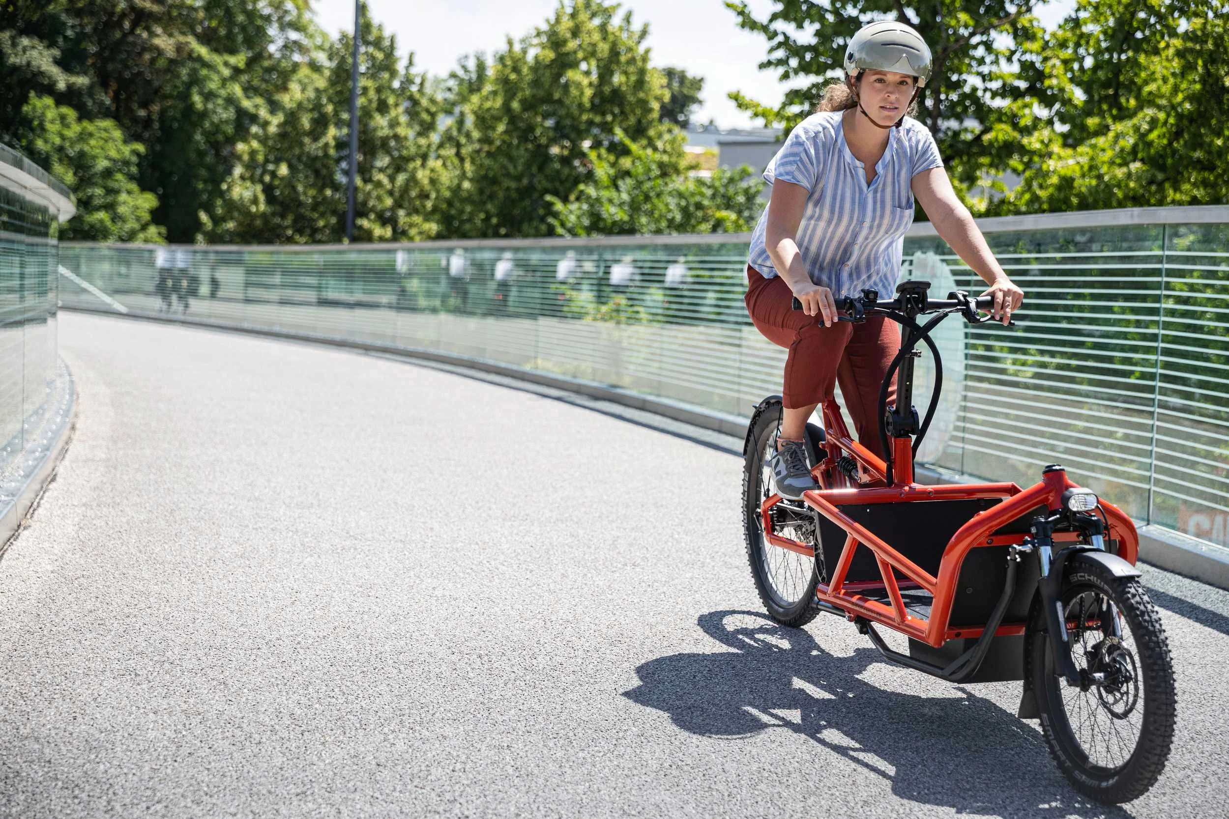 Frau fährt Riese & Müller Cargobike über eine Brücke in der Stadt