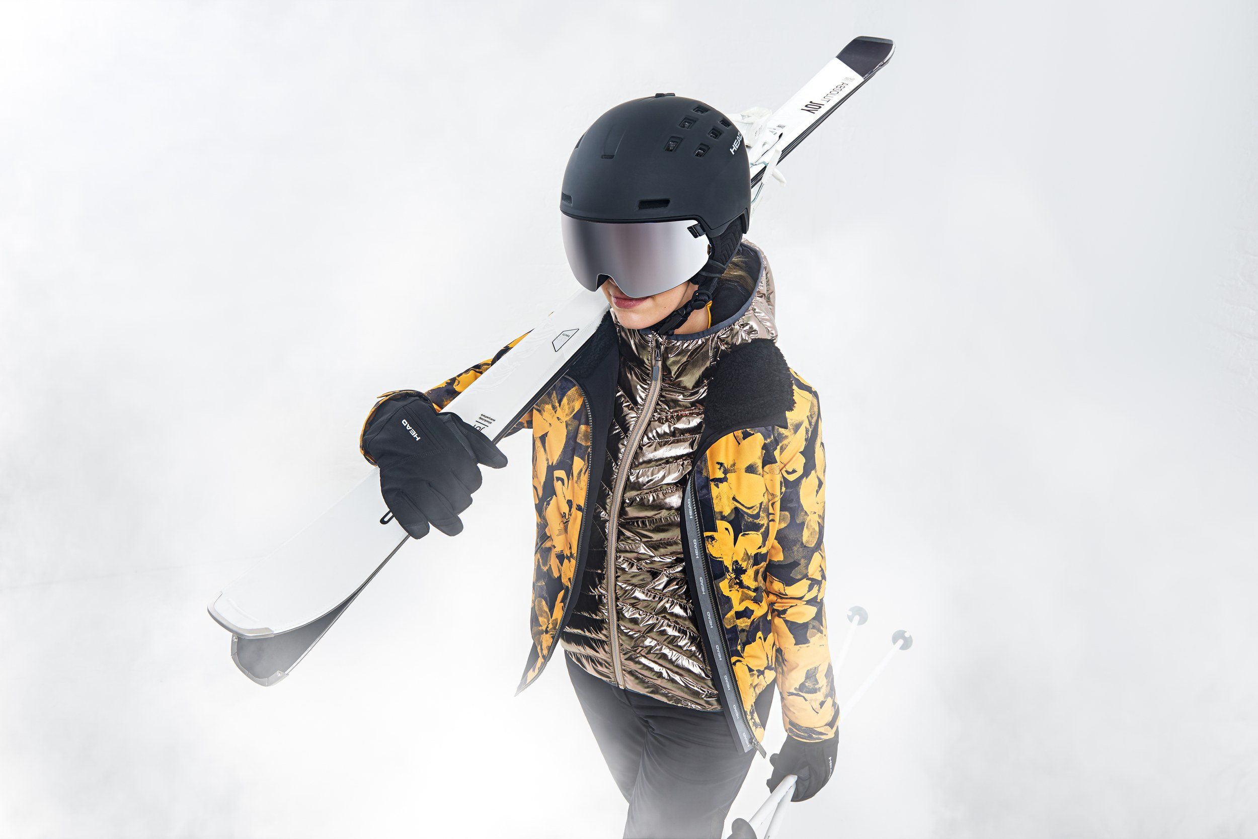 Skifahrerin trägt Ski über der Schulter im Nebel