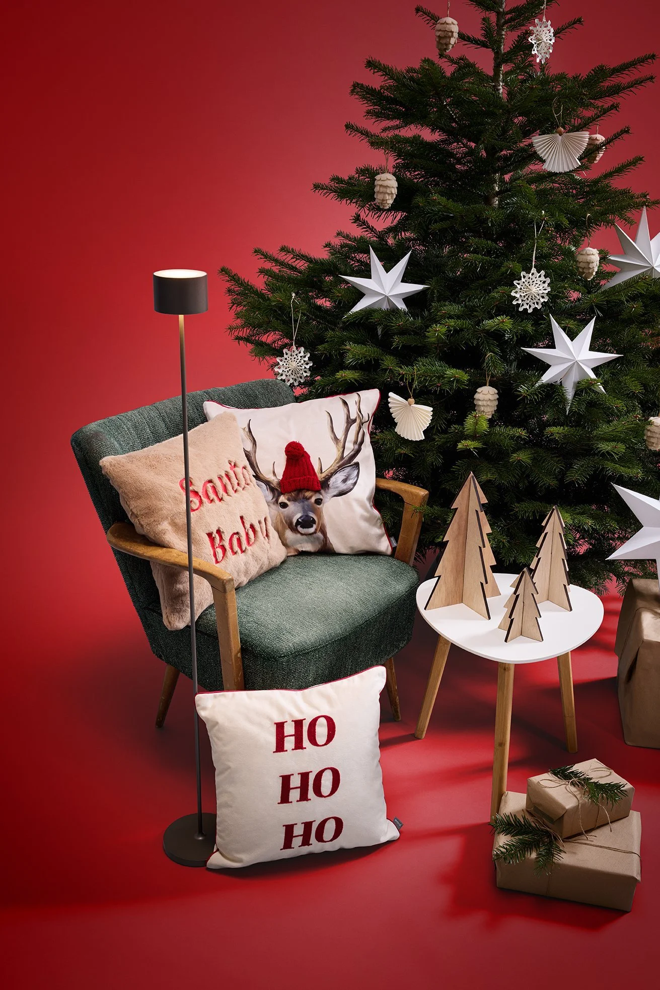 Weihnachtliches Wohn-Set mit Baum, Sternen und Deko-Kissen vor rotem Hintergrund für Zinser – Retusche Bildergut.