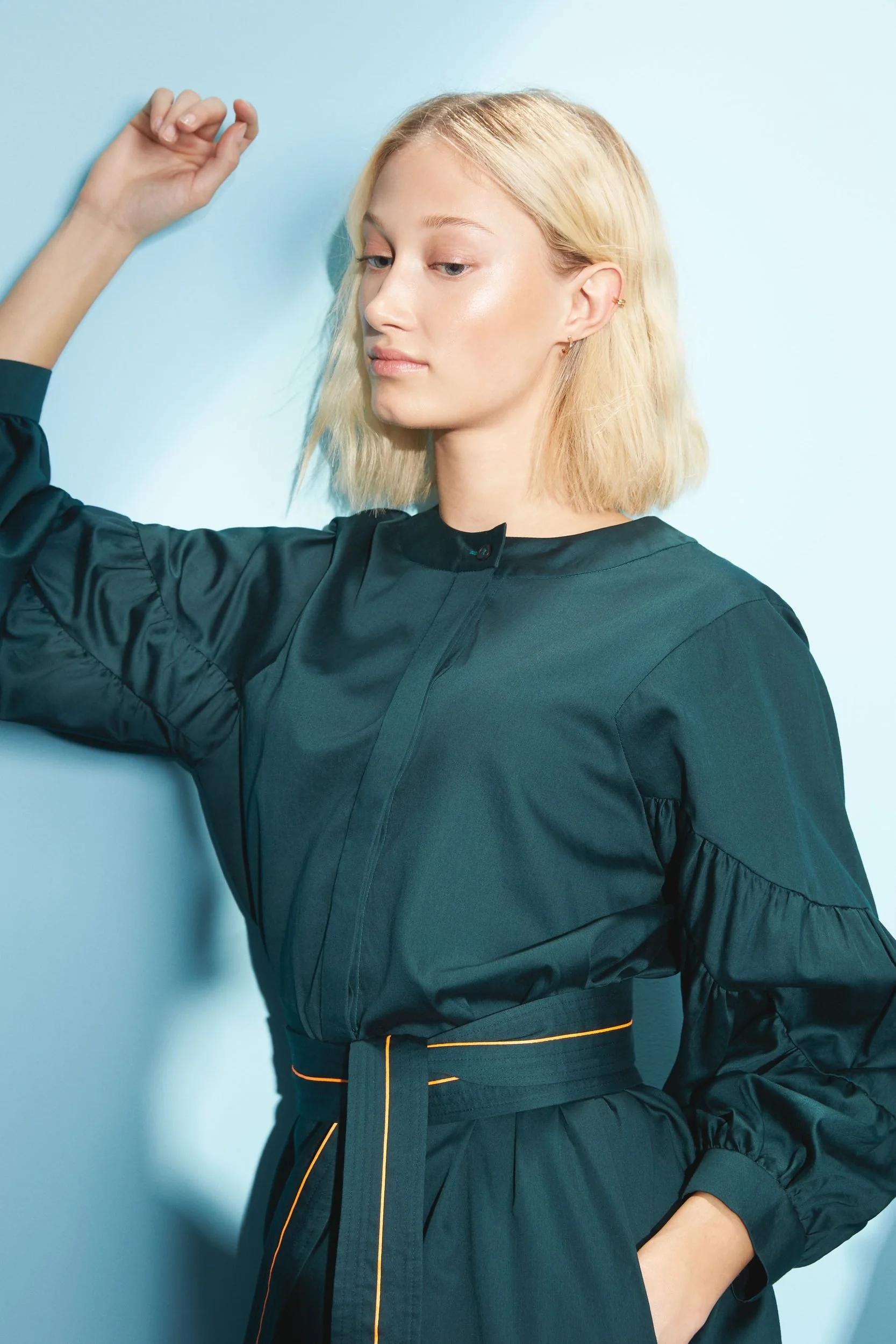 Hellmuth Lookbook SS20: dunkelgrüner Look DUBLIN, an die Studiowand gelehnt