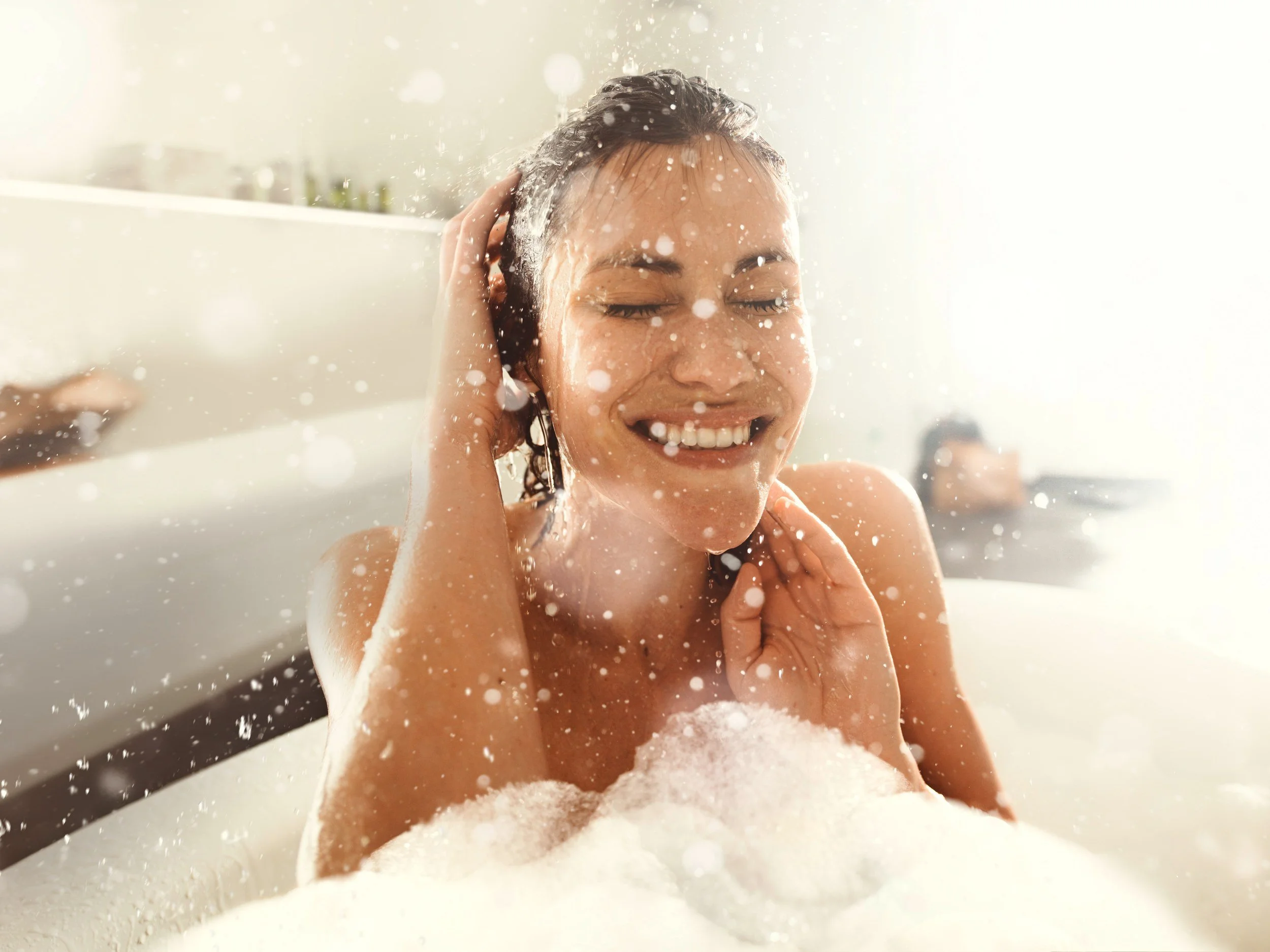 Lachende Frau in der Wanne mit Schaumflocken