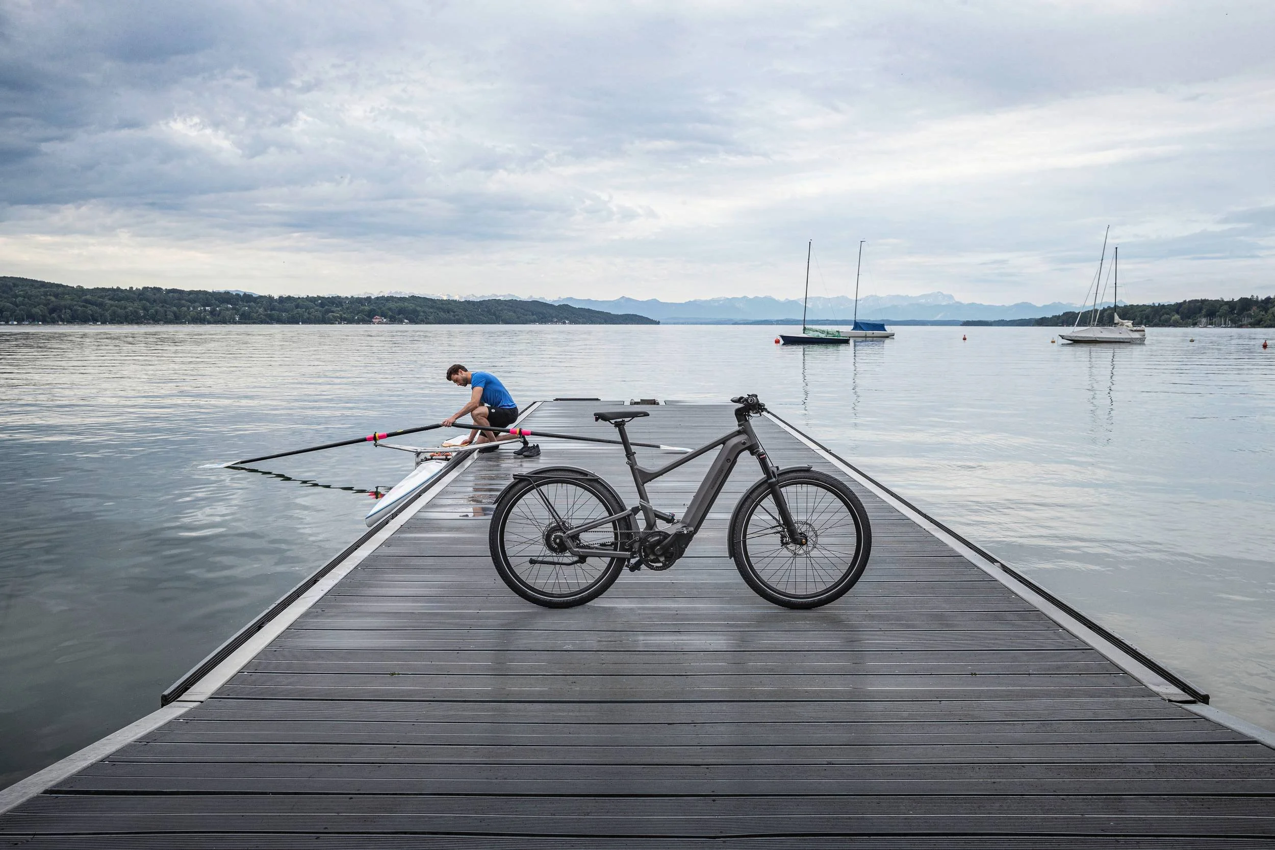 Riese & Müller E-Bike auf Bootssteg am See mit Ruderer