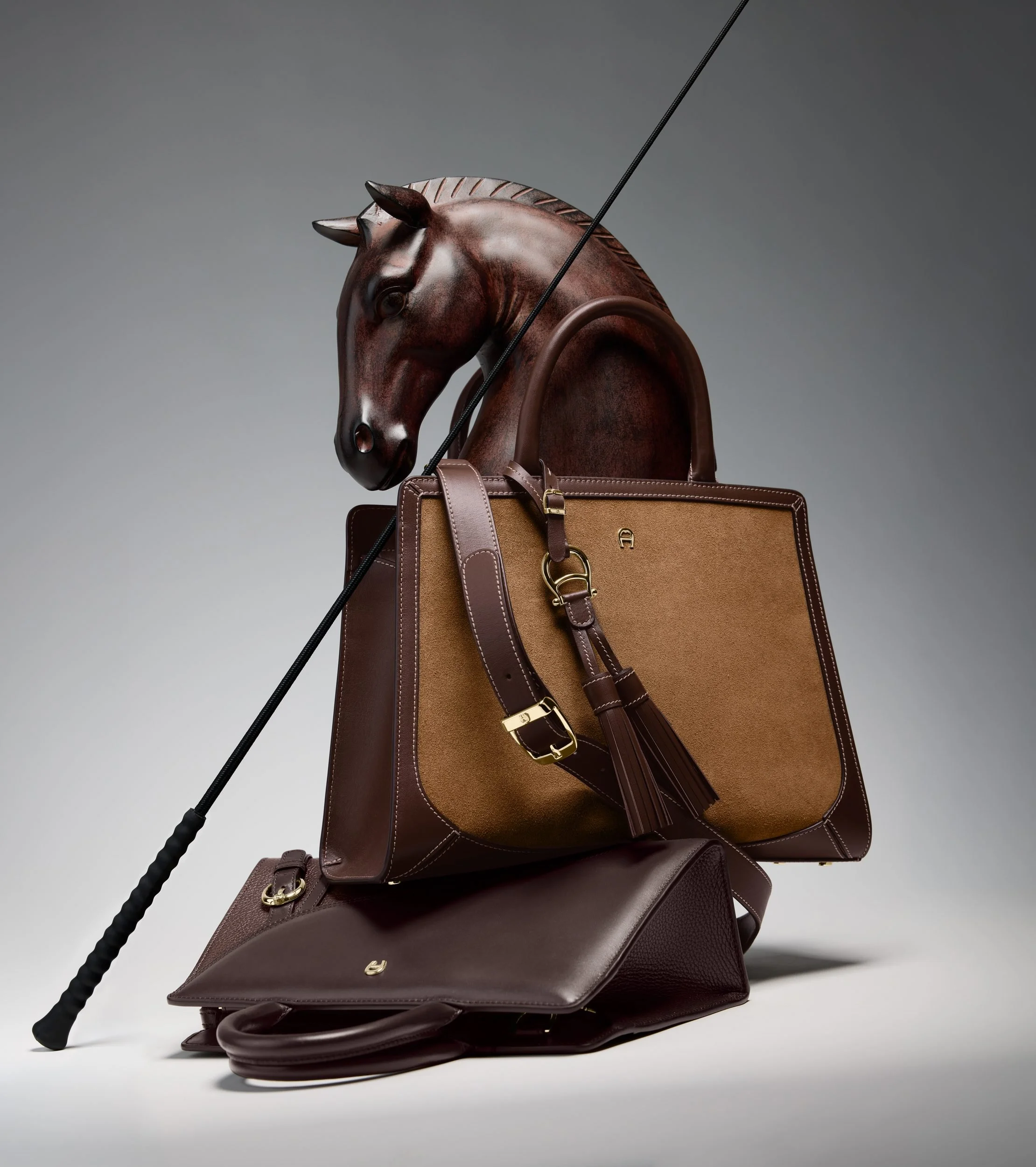 AIGNER Fall-Winter 2026: CYBILL-Tasche und Lederwaren an einer Pferdeskulptur mit Gerte
