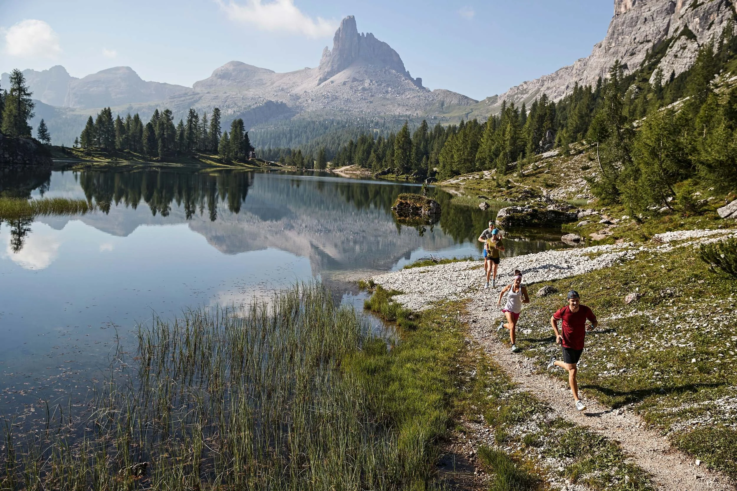 Trailrunner am stillen Bergsee mit Spiegelung der Dolomitengipfel