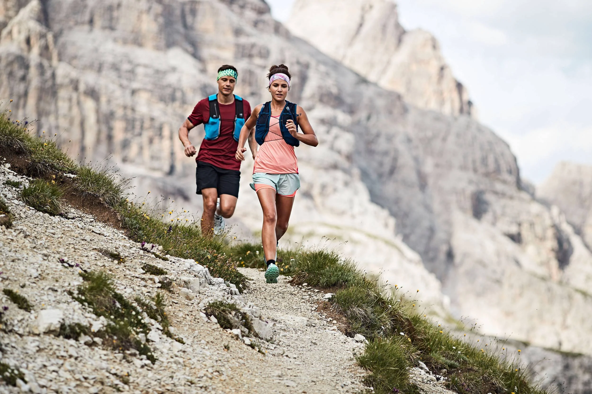 Trailrunner-Paar mit BUFF Stirnbändern läuft Geröllpfad in den Dolomiten hinab