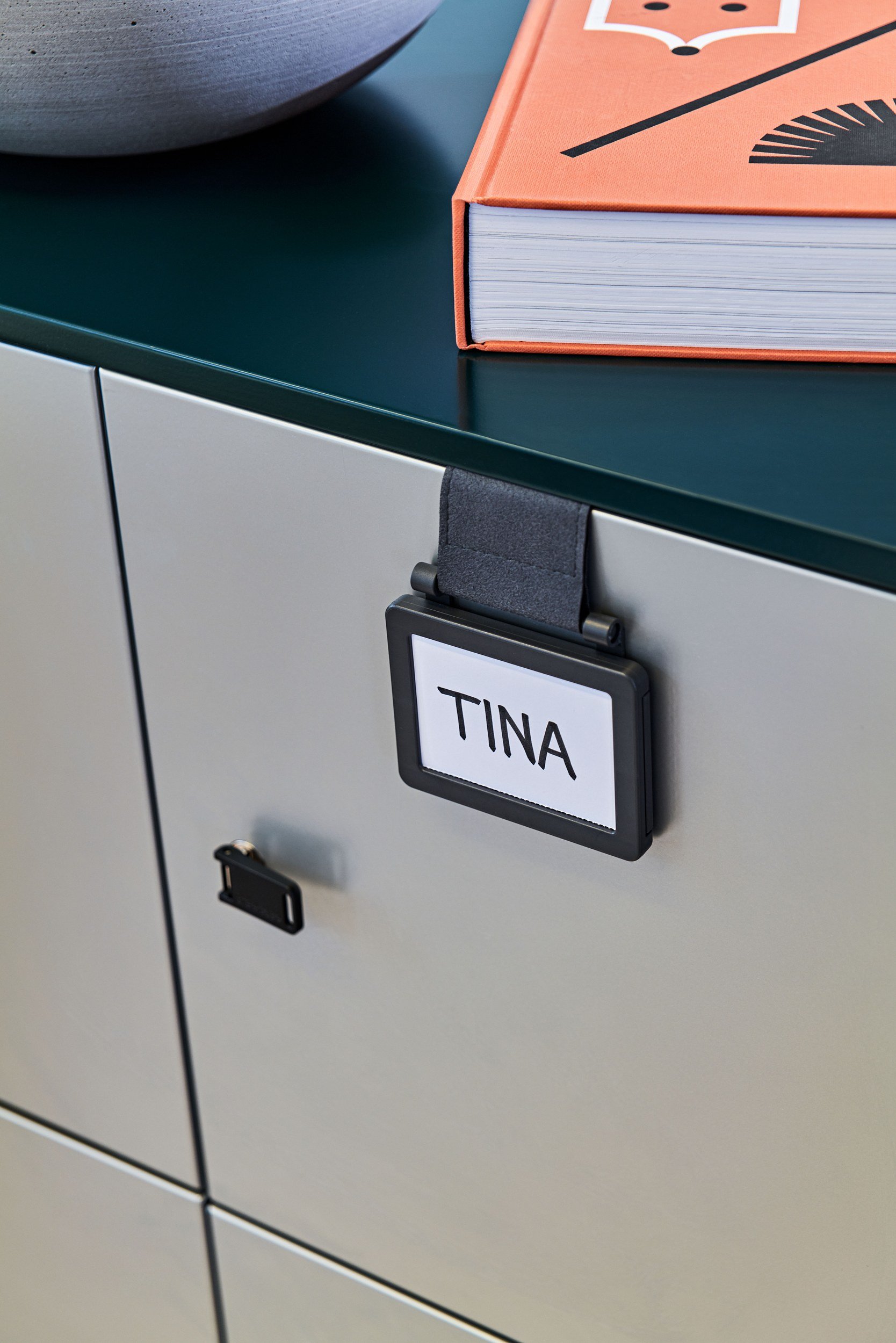 Detail eines Steelcase Rollcontainers mit Namensschild Tina und orangefarbenem Buch