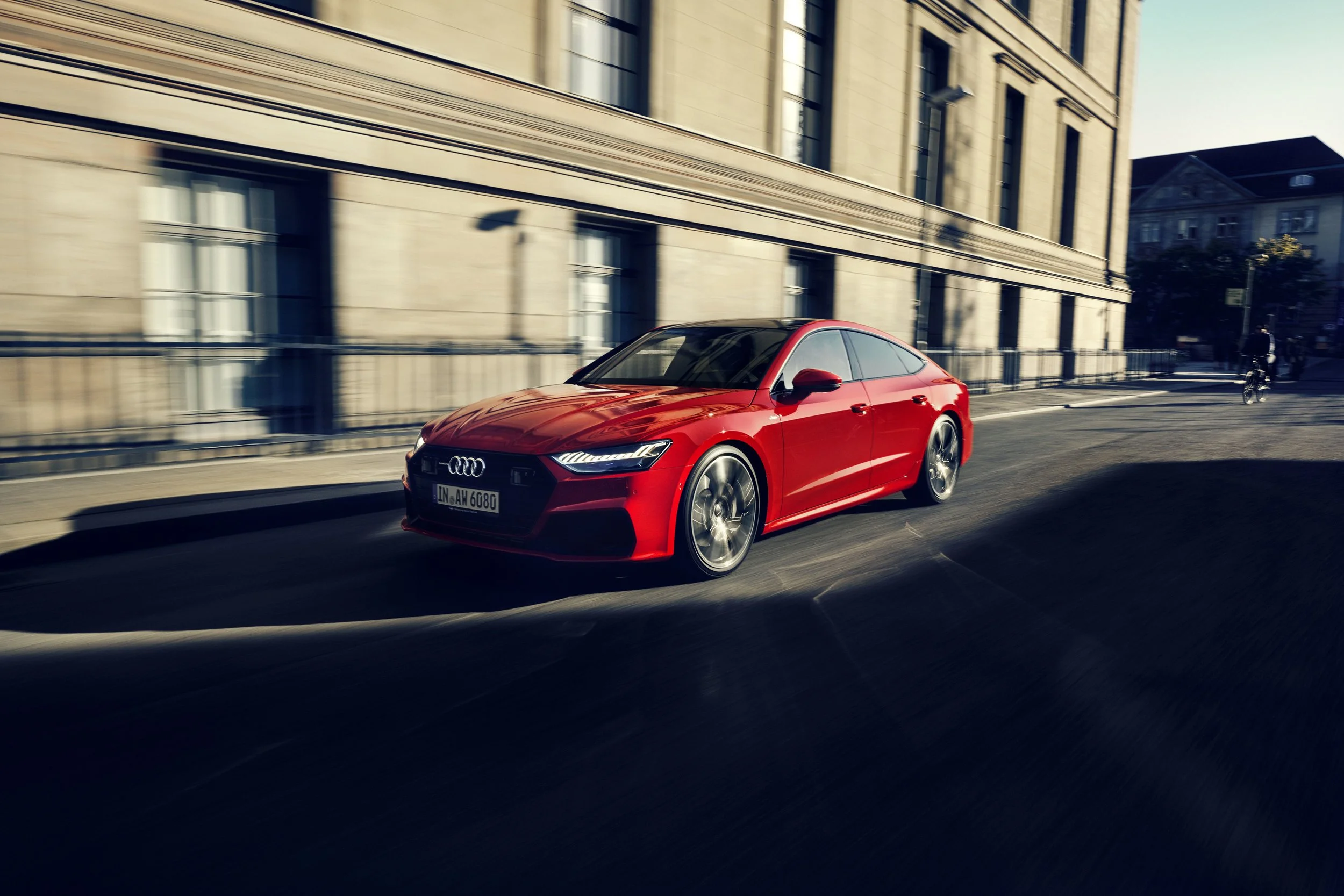 Roter Audi A7 in Bewegung entlang einer Altbaufassade bei Sonnenlicht – Look and Feel Retusche von Bildergut.