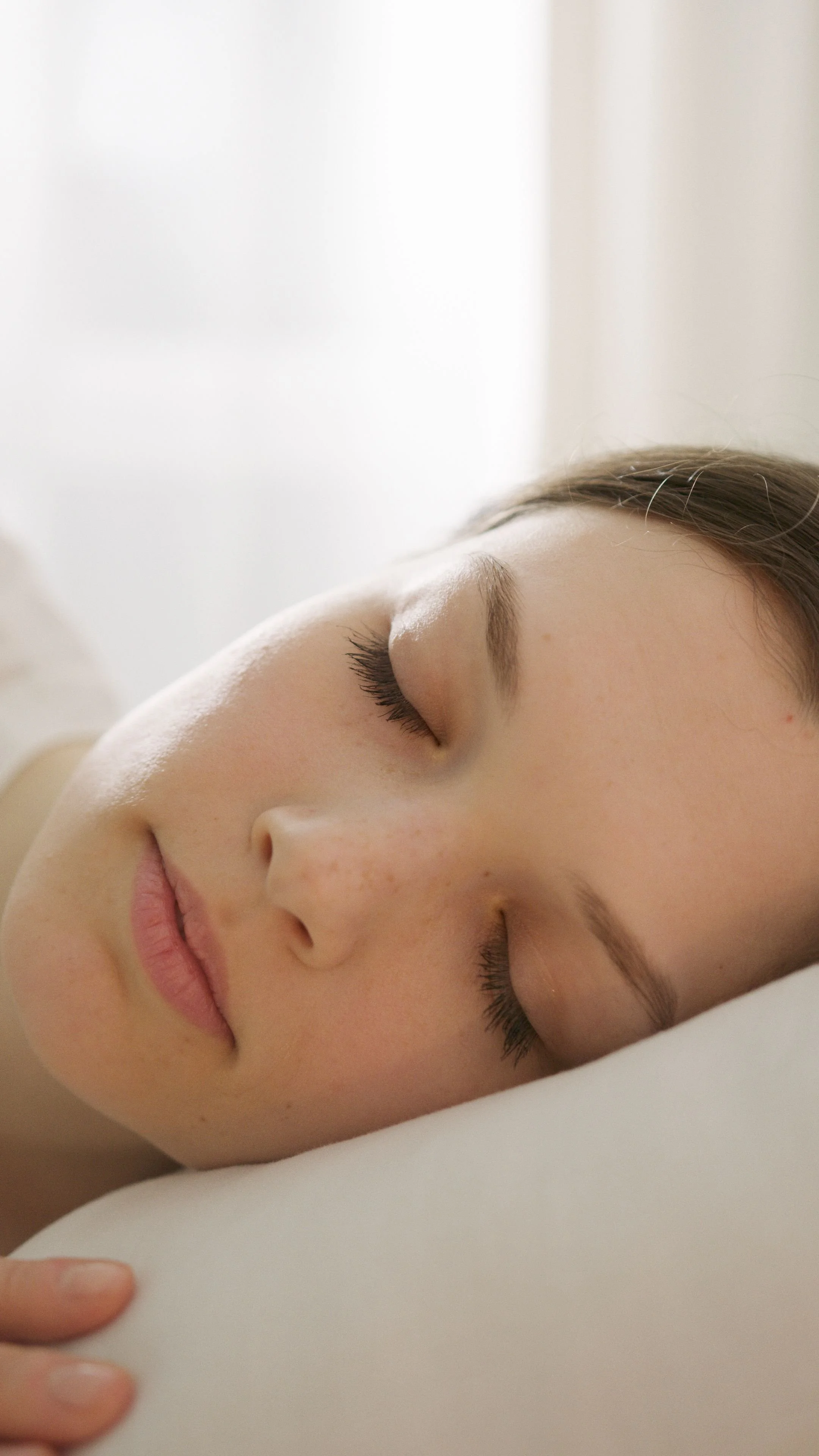 Nahaufnahme eines schlafenden Mädchens mit geschlossenen Augen, entspannter Mimik und glatter Haut, ruhiger Hintergrund. Modul 10. Schlaf bei Tinnitus.