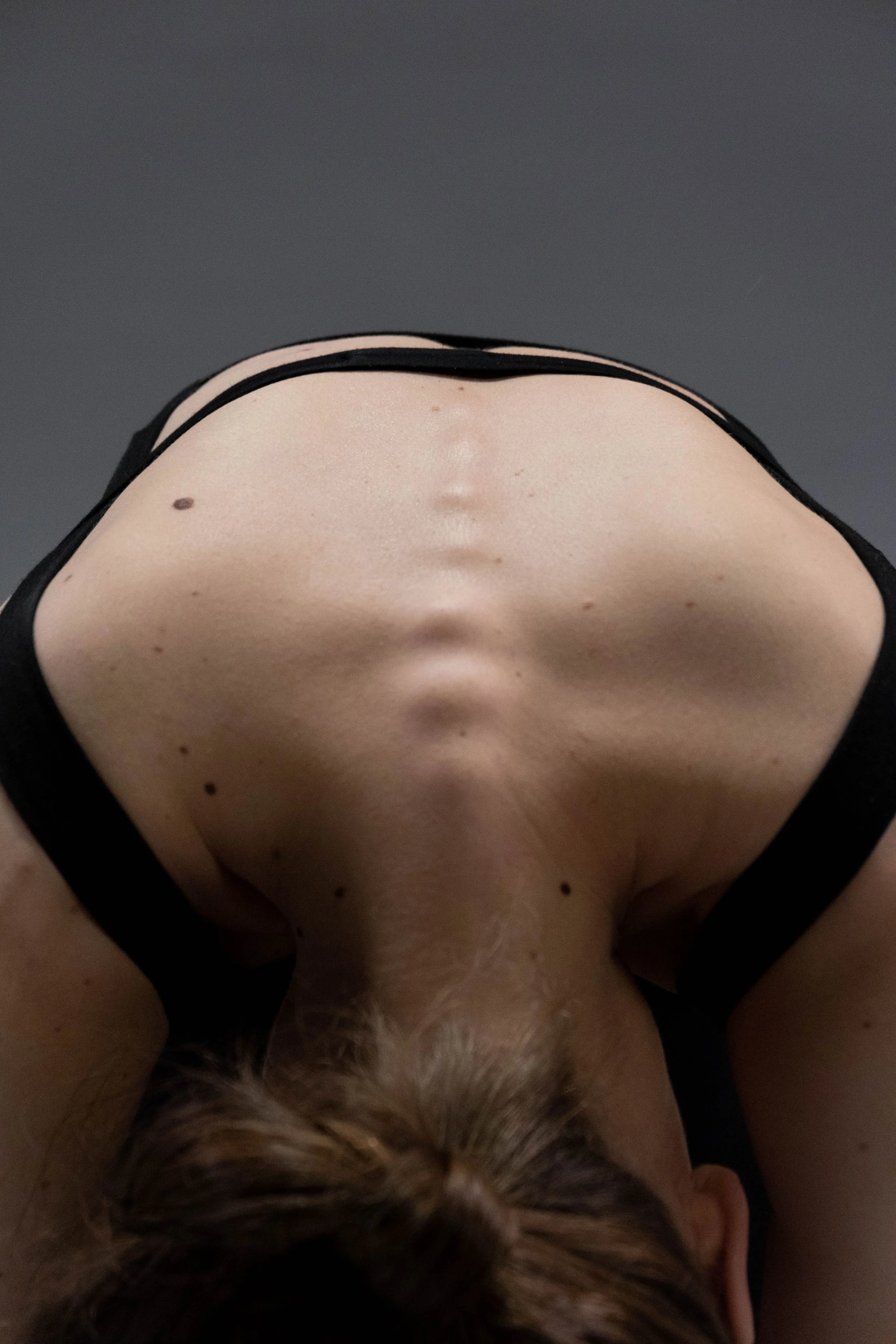 Oben eine nackte menschliche Brust mit einigen Muttermalen, darunter schwarze Kleidung. Unten ist das Gesicht eines Hundes mit braun-weißem Fell und braunen Augen zu sehen, der nach oben schaut. Modul 12. Übungen für die Wirbelsäule bei Tinnitus.