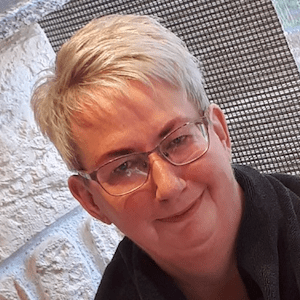 Ein älterer Mann mit kurzen, grauen Haaren und Brille lächelt.