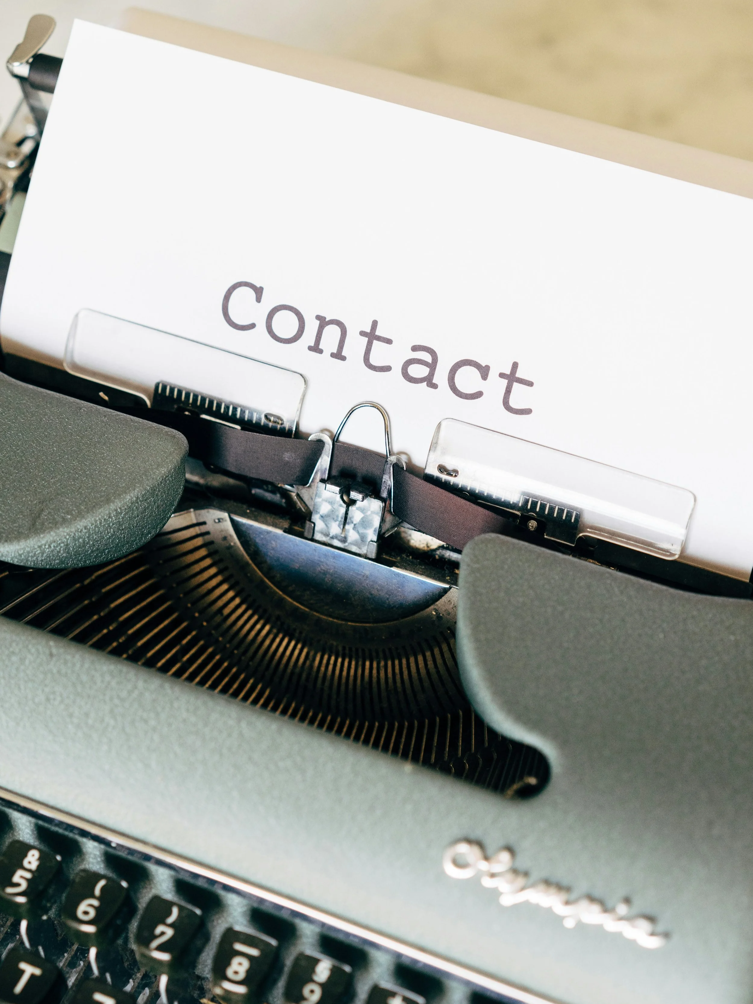 Vintage typewriter with the word “Contact” typed on paper.