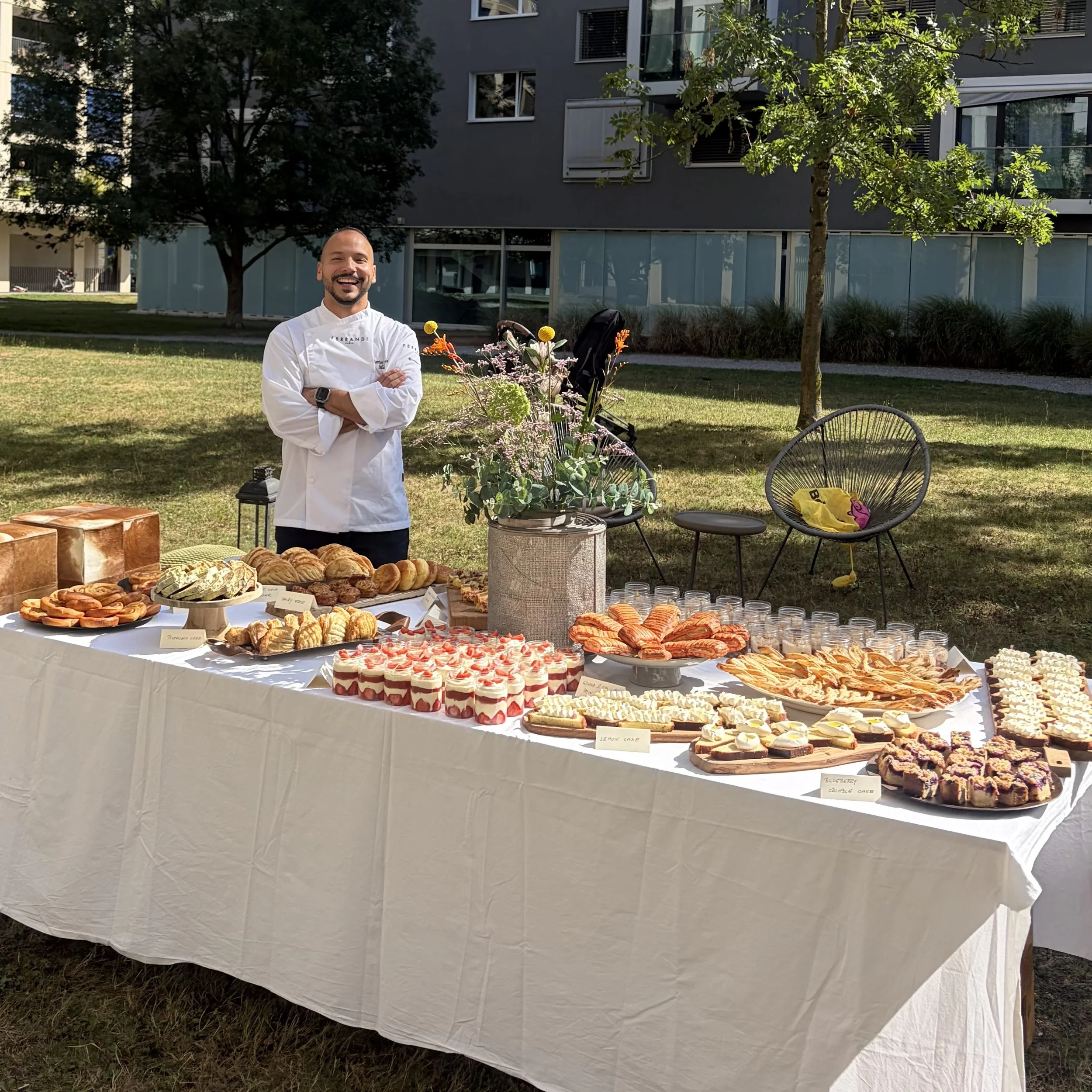 Pastry chef Julio Ferreira presenting an outdoor catering table with assorted pastries.