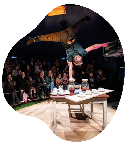 Teacrobat: Akrobat im einarmigen Handstand auf einem Glas