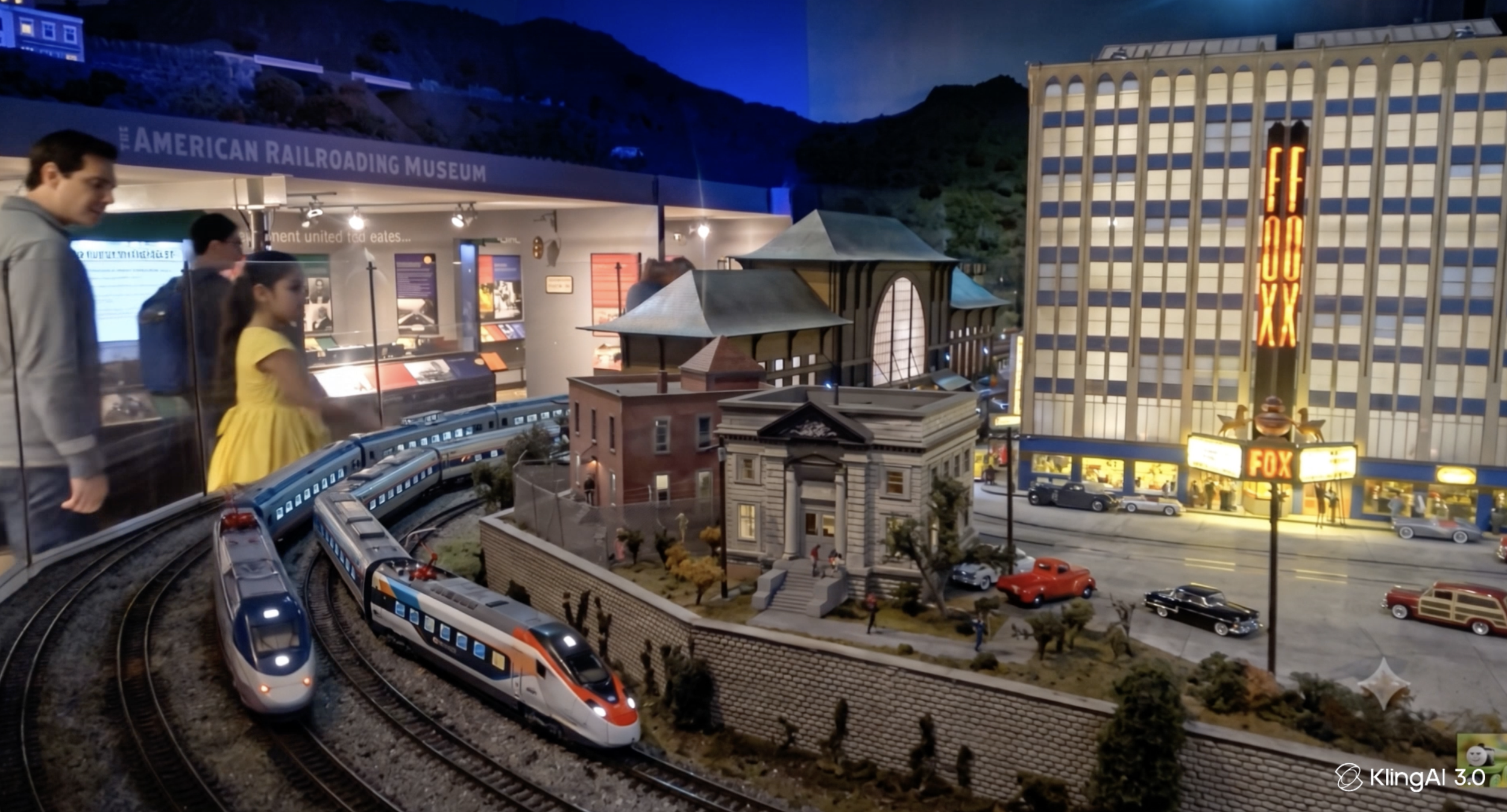 Model train exhibit with detailed miniature buildings, streets, cars, and a moving train, set indoors at the American Railroad Museum, with visitors observing the display.