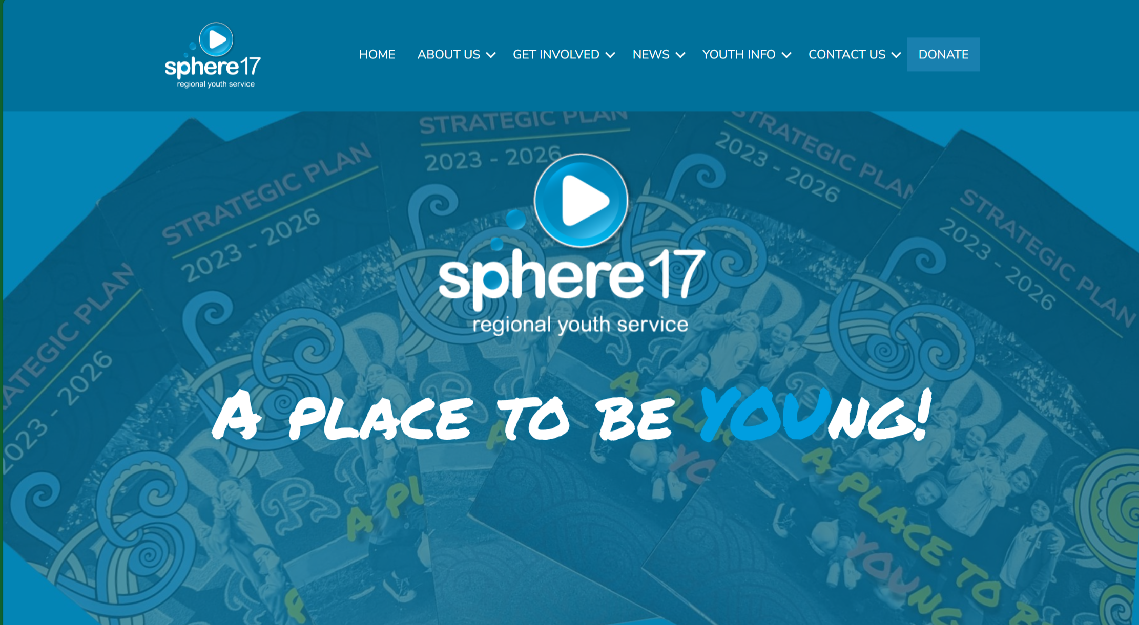 Screenshot of the homepage of Sphere 17, a regional youth service organisation, featuring a blue background with a play button icon, the organisation’s logo, and a slogan that reads "A PLACE TO BE YOUNG!", with the YOU highlighted in the word young.