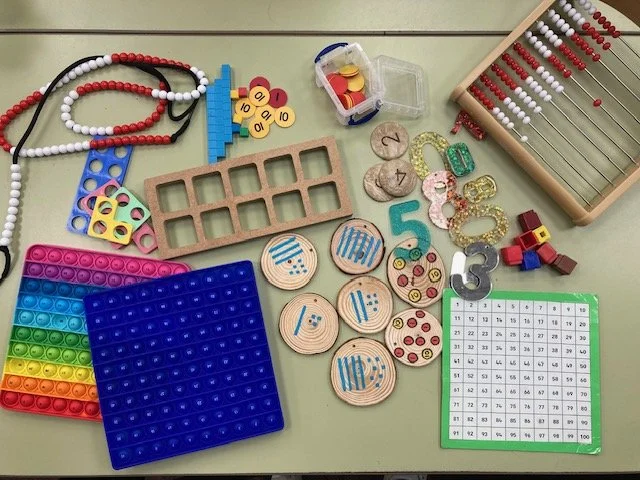 Educational toys and tools for math and counting, including abacus, number blocks, counting chips, colorful pegboard, number cards, dice, and a number chart.