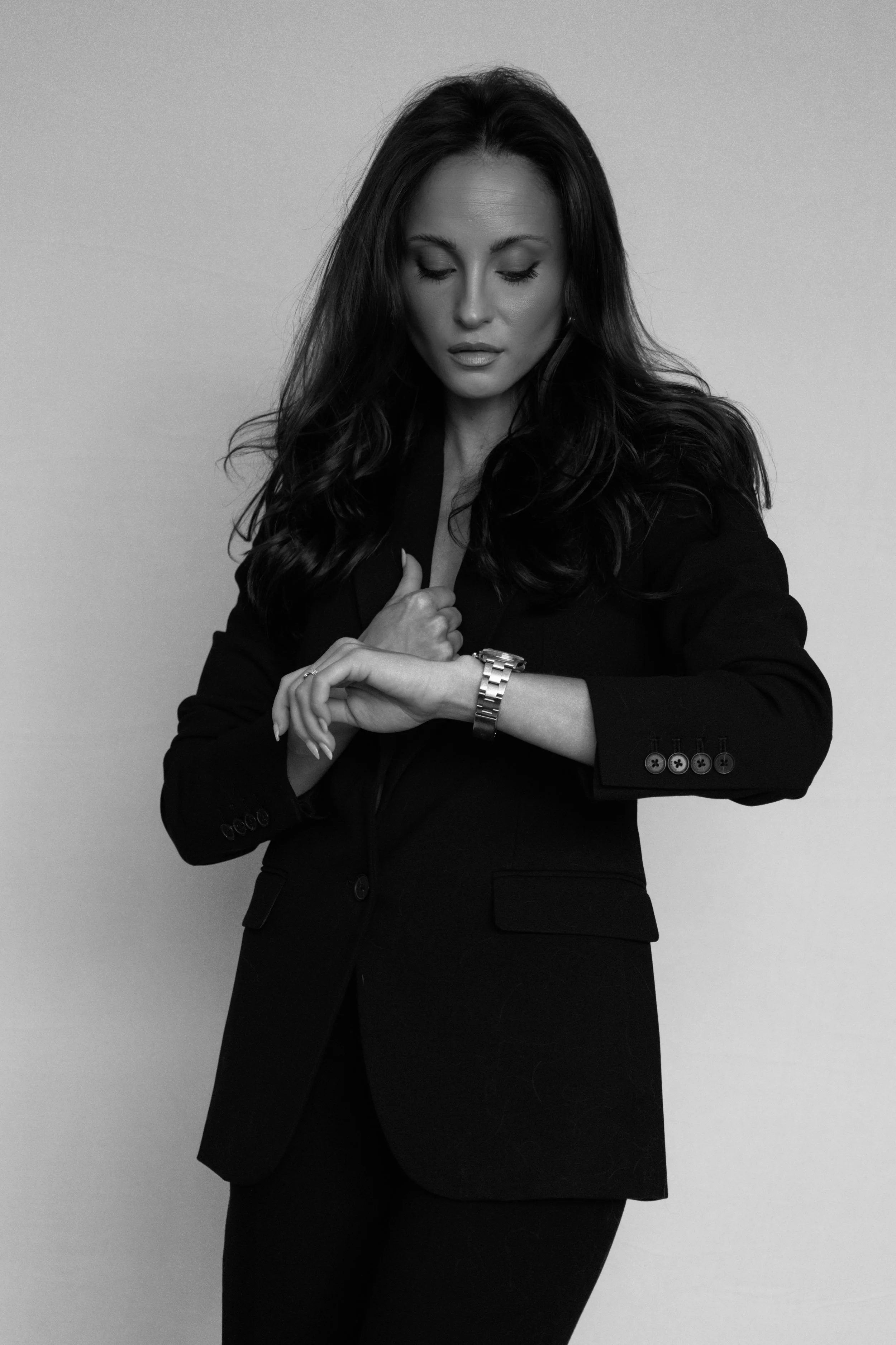 Black-and-white portrait of the Kolt Following founder standing in a black suit with her hands clasped.