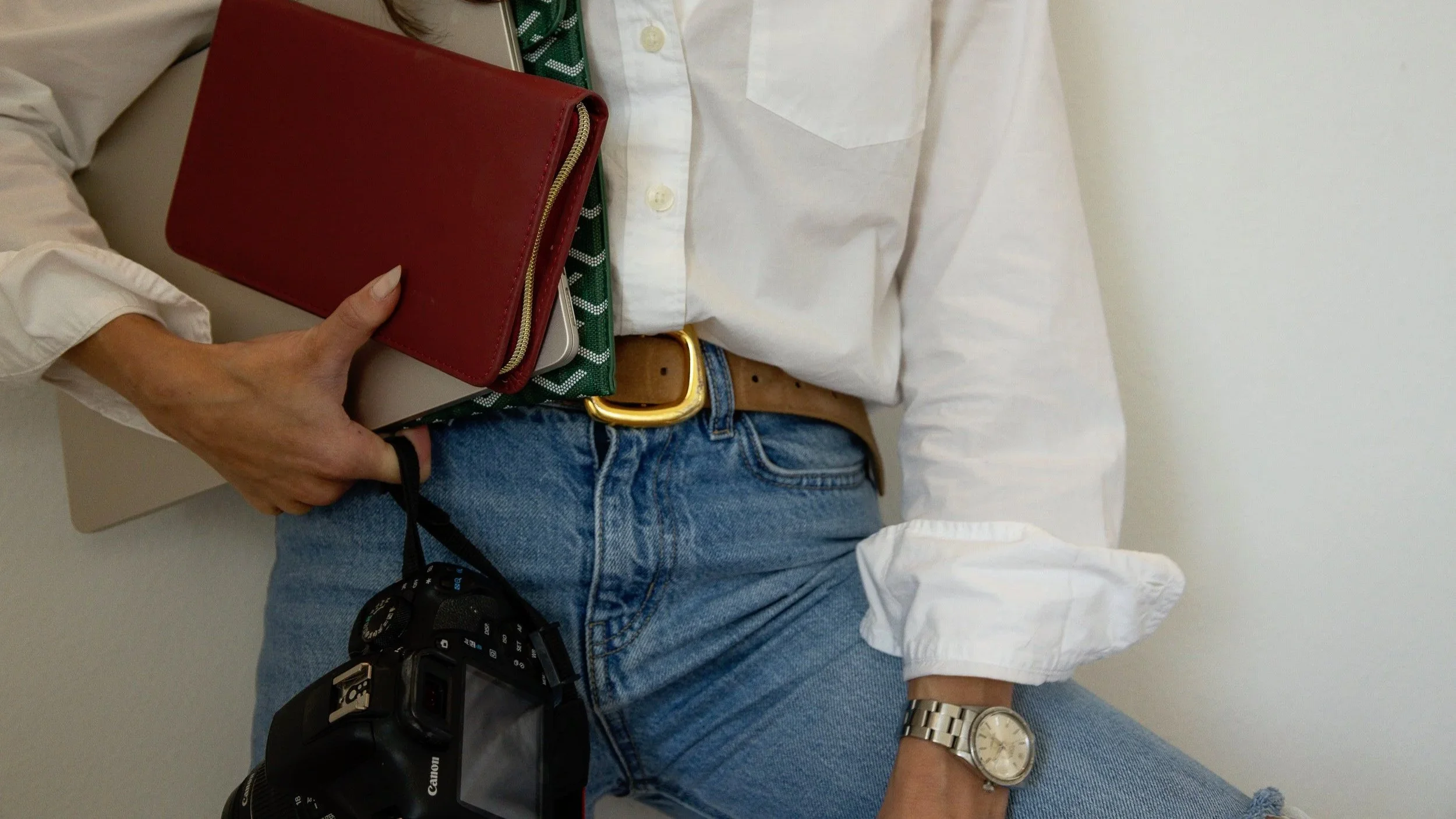 Close-up of a person holding a camera and a red zippered case.