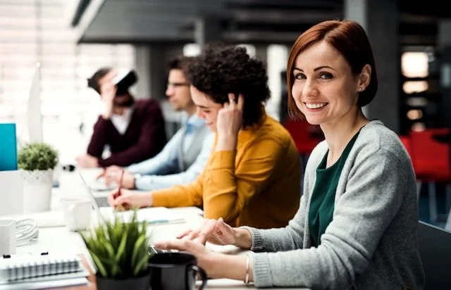 Group of four women sitting at a conference table in an office, engaged in a meeting or discussion.