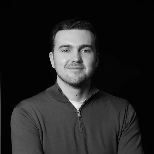 Portret van een man met korte donker haar, in een donkergrijze sportjack, lachend, zwart-wit