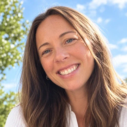 Smiling woman with long brown hair outdoors under a bright blue sky