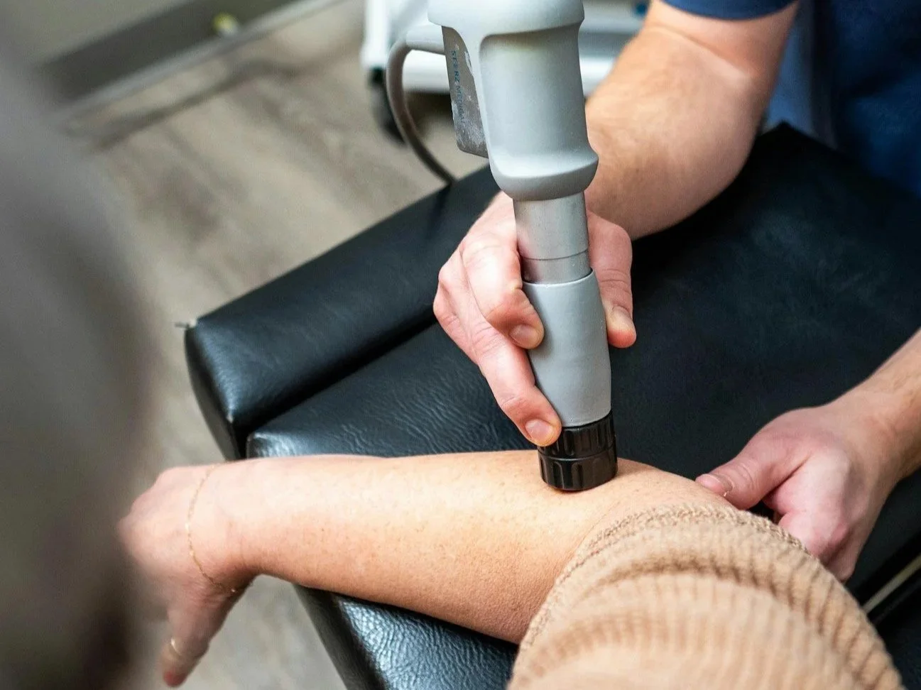 Physical therapist using a handheld Shockwave therapy Bruntsfield  on a patient’s calf muscle