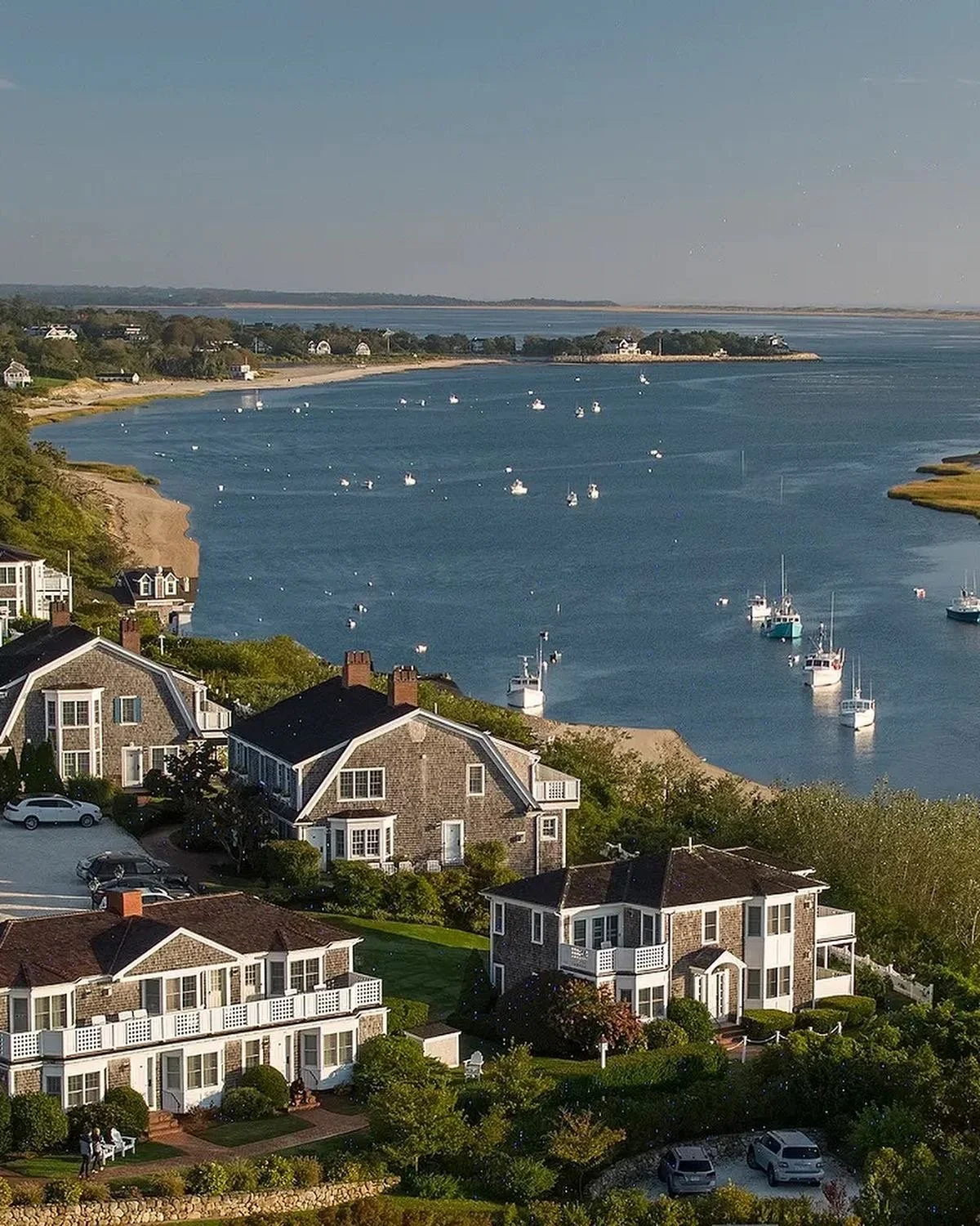 Coastal neighborhood with houses and apartments near a body of water with sailboats and a shoreline in the distance