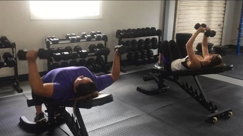 Women performing dumbbell chest flys during Body By U Fit strength training in Central Houston