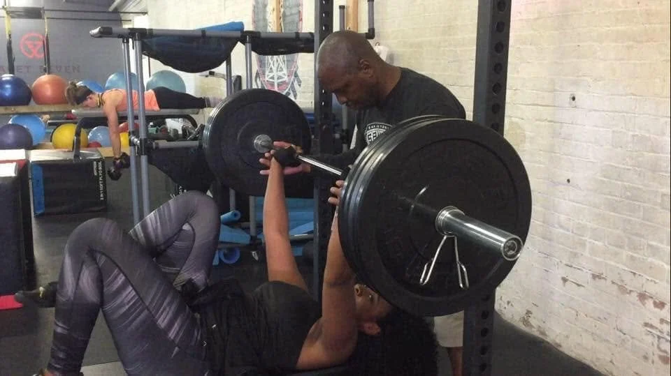Coach Phil performing a one-on-one fitness assessment with a new client at Body By U Fit in Central Houston before starting a personalized women's strength training program.
