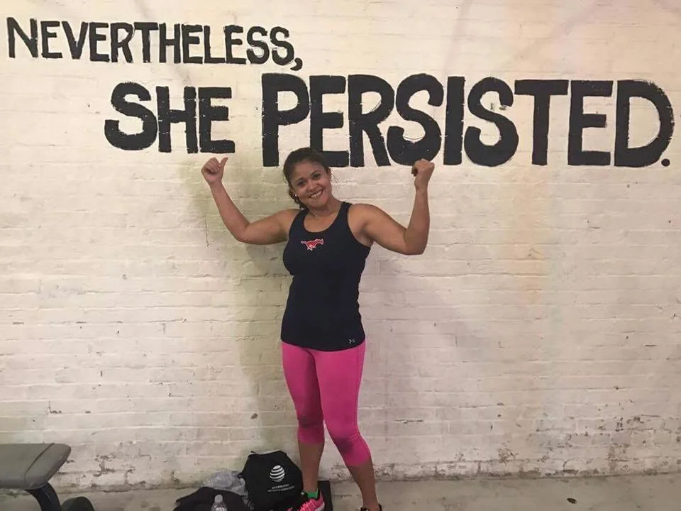 Body By U Fit client standing beneath the words "Nevertheless, She Persisted," representing strength, resilience, and confidence through women's strength training.